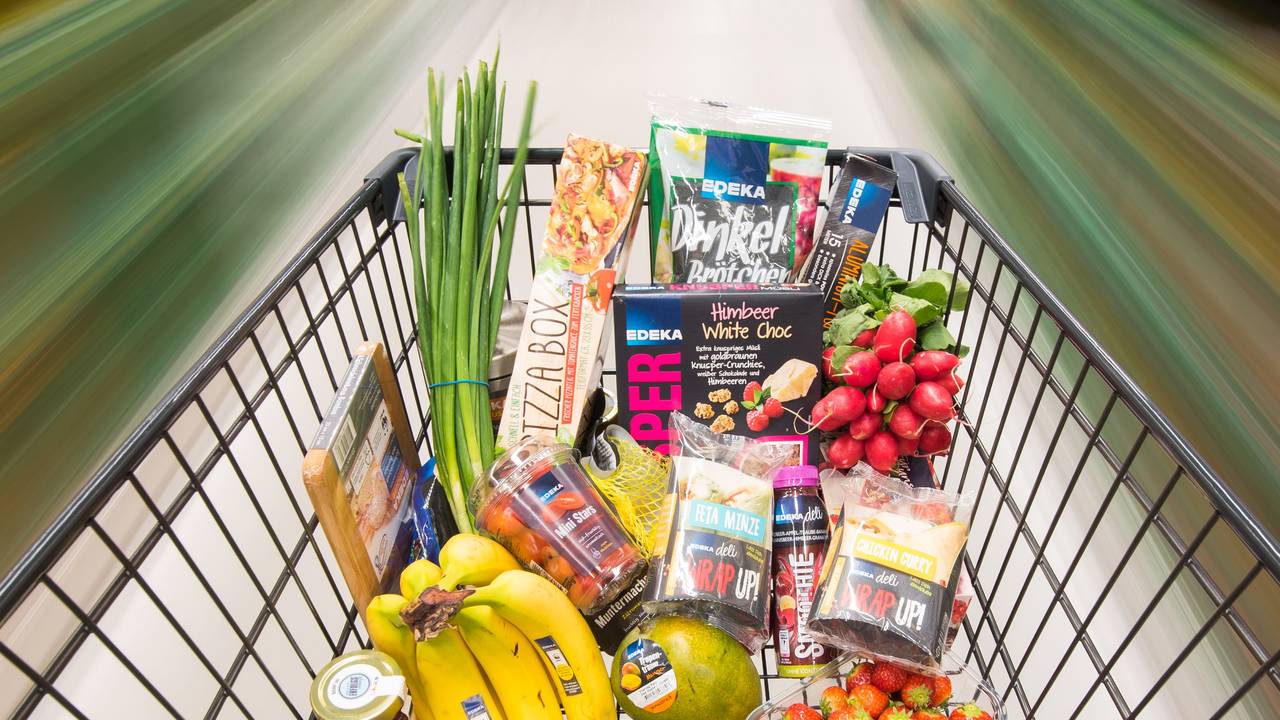 Ein Einkaufswagen mit Edeka-Produkten wird durch einen Supermarkt geschoben