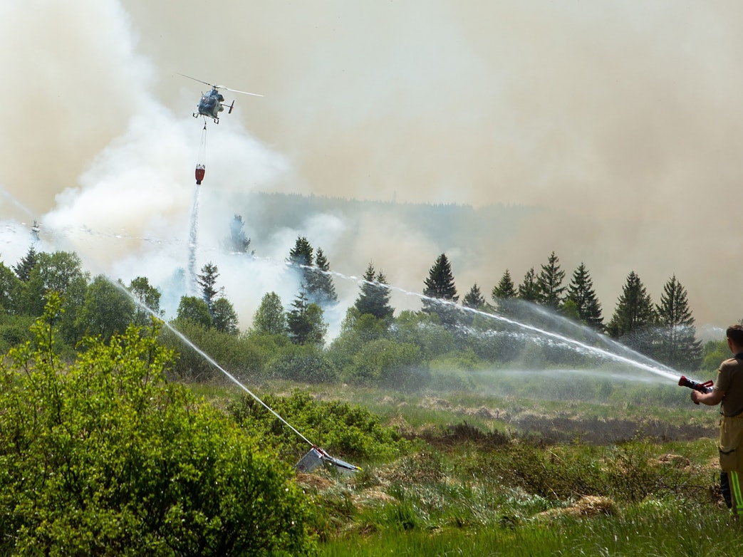 Die Feuerwehr versucht mit einem Hubschrauber einen Moorbrand im deutsch-belgischen Grenzgebiet bei Aachen zu löschen. Das Feuer sei auf belgischer Seite im Hohen Venn ausgebrochen, teilte am 30. Mai 2023 die Städteregion Aachen mit.