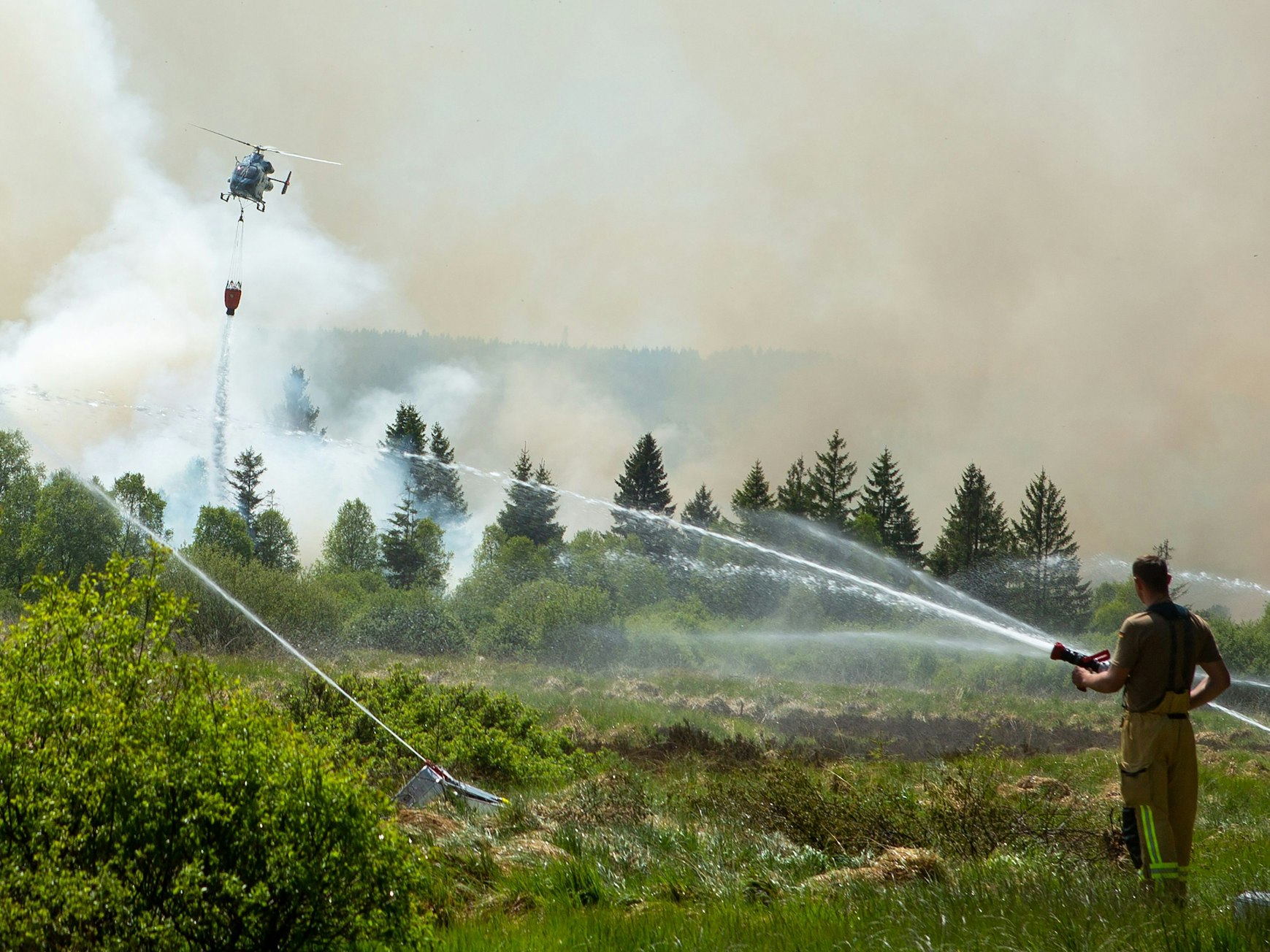 Die Feuerwehr versucht mit einem Hubschrauber einen Moorbrand im deutsch-belgischen Grenzgebiet bei Aachen zu löschen. Das Feuer sei auf belgischer Seite im Hohen Venn ausgebrochen, teilte am 30. Mai 2023 die Städteregion Aachen mit.