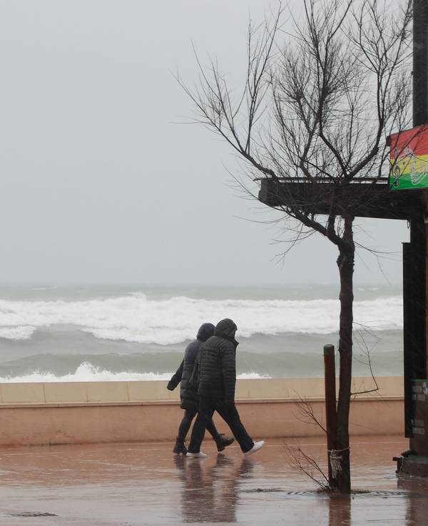 Ein Paar geht bei stürmischem Wetter an der Strandpromenade von Can Picafort spazieren.