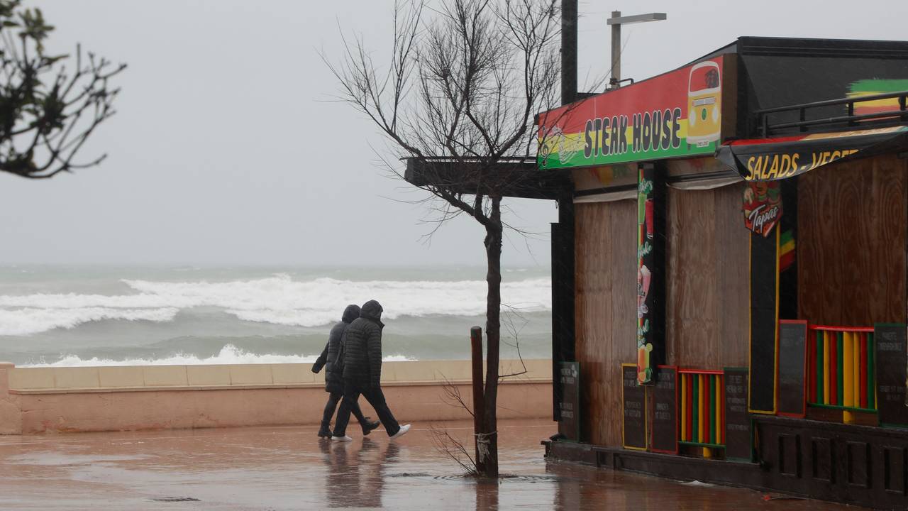 Ein Paar geht bei stürmischem Wetter an der Strandpromenade von Can Picafort spazieren.