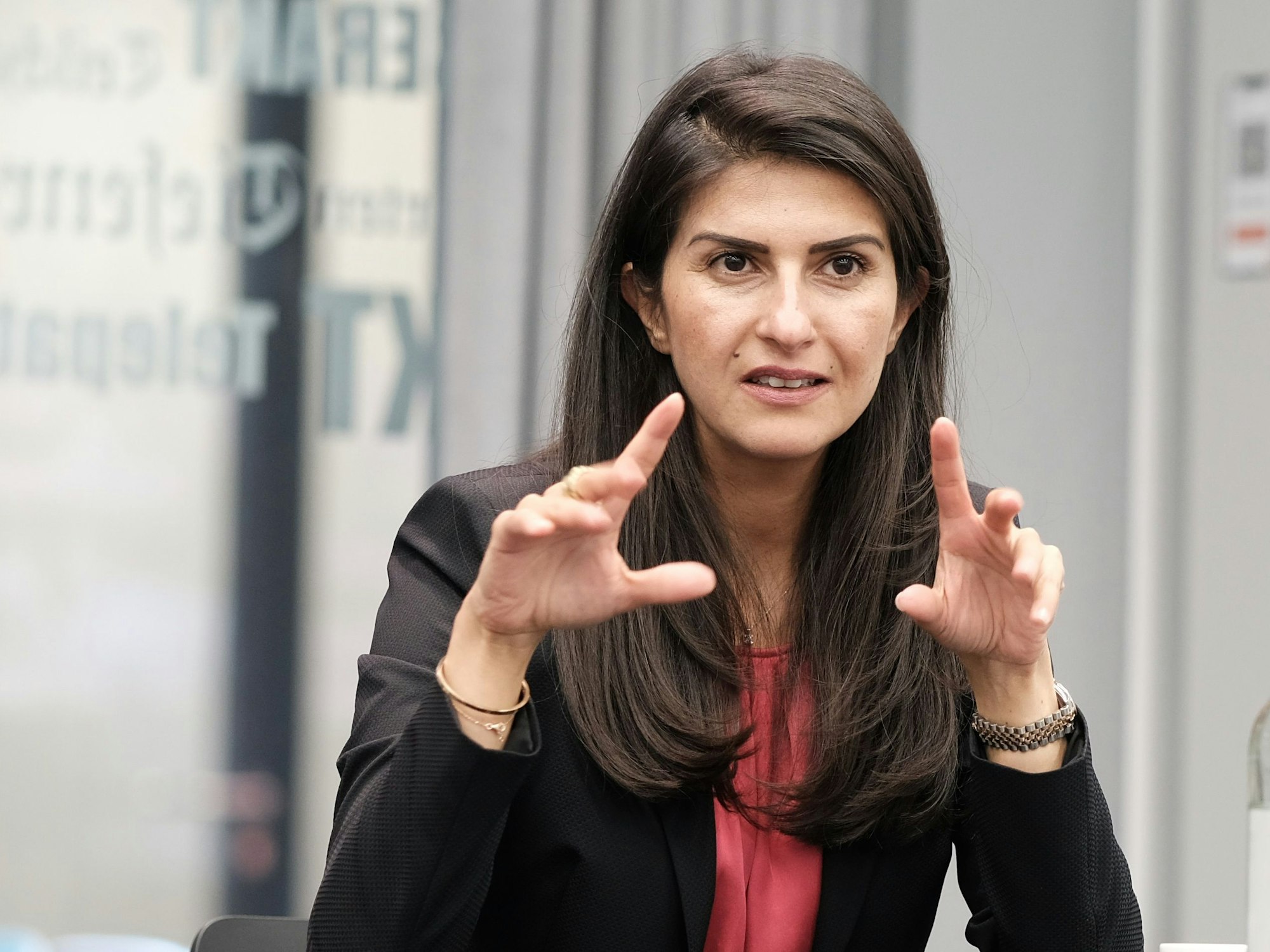 Serap Güler sitzt bei einer Pressekonferenz und gestikuliert mit ihren Händen.