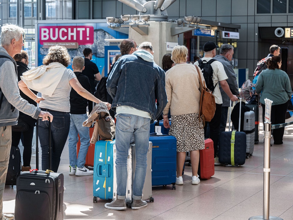 Fluggäste stauen sich mit ihrem Gepäck an Check-In-Schaltern.