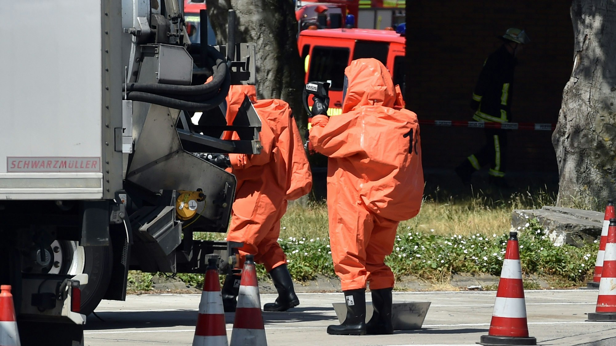 Feuerwehrleute in ABC Schutzanzügen kontrollieren einen Gefahrguttransporter