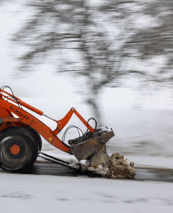Ein Radlader räumt den Schnee von einem Weg.