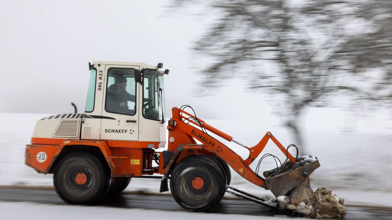 Ein Radlader räumt den Schnee von einem Weg.