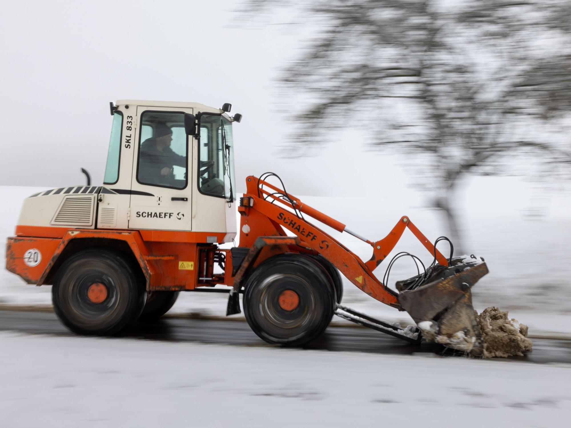 Ein Radlader räumt den Schnee von einem Weg.