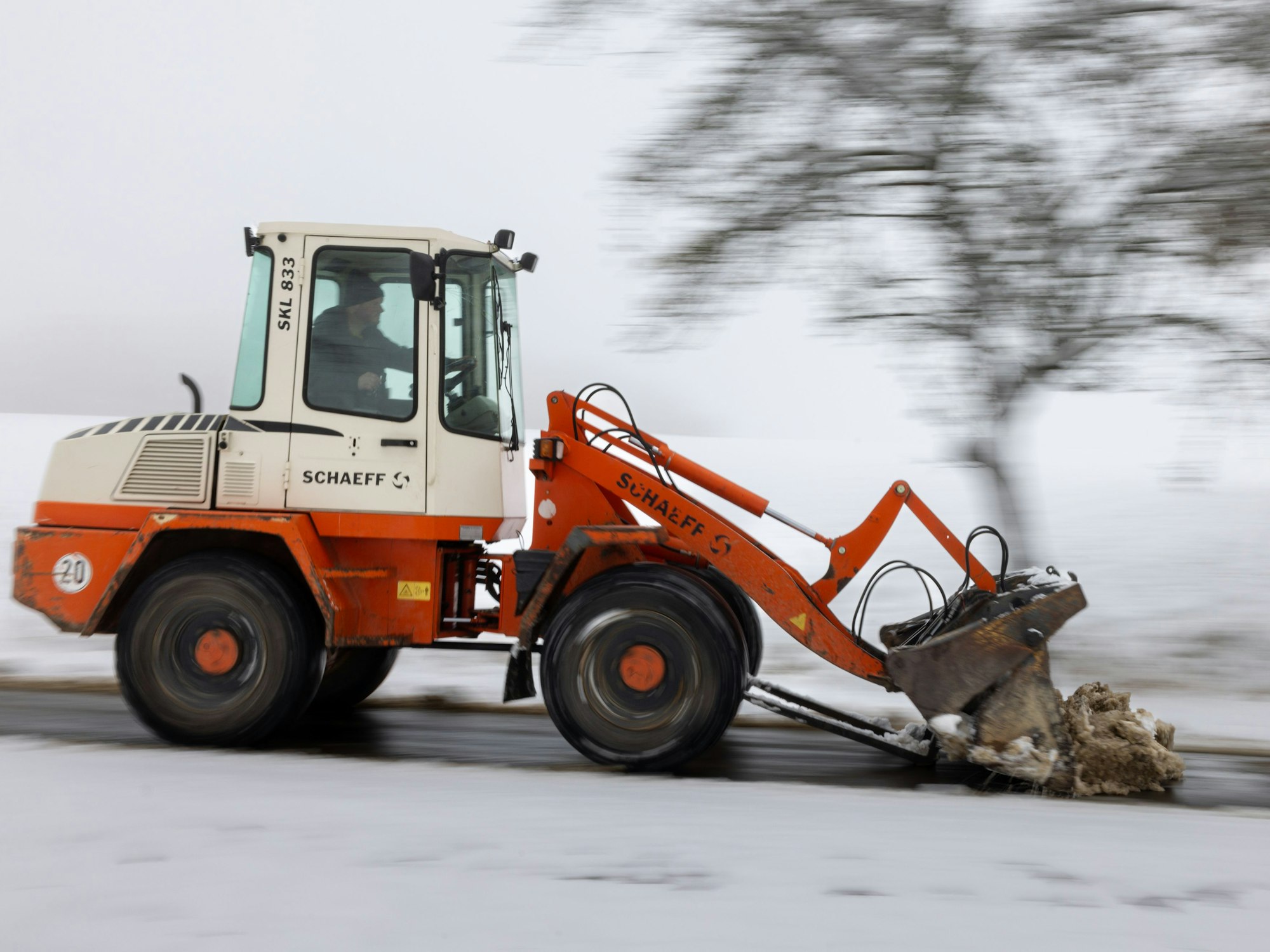 Ein Radlader räumt den Schnee von einem Weg.