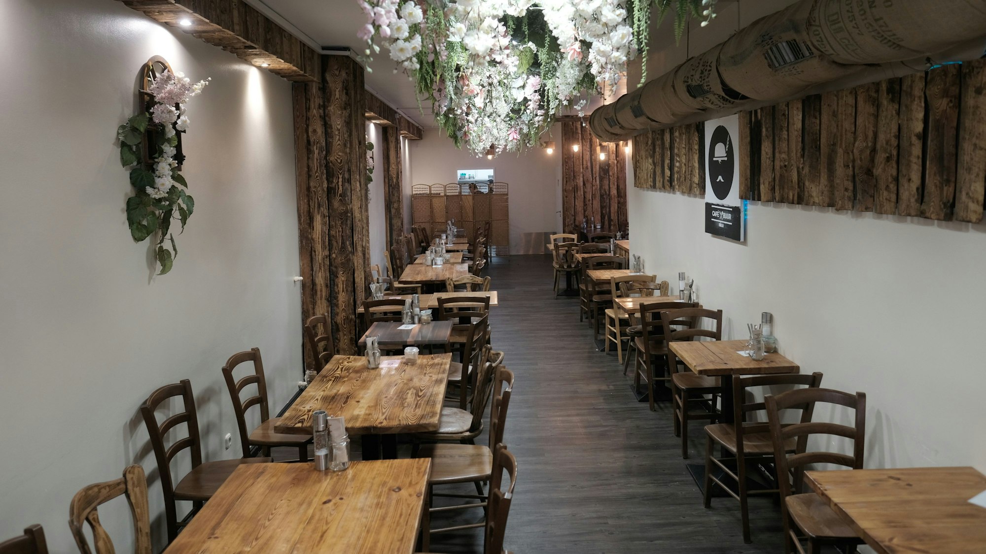 Blick in das leere Café Buur in Köln. Holztische und Stühle stehen sauber aufgereiht.