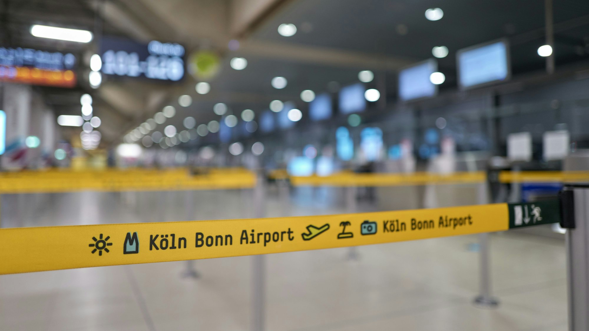 Sperrbänder in gelber Farbe leiten am Flughafen Köln/Bonn die Menschen zu ihren Schaltern.