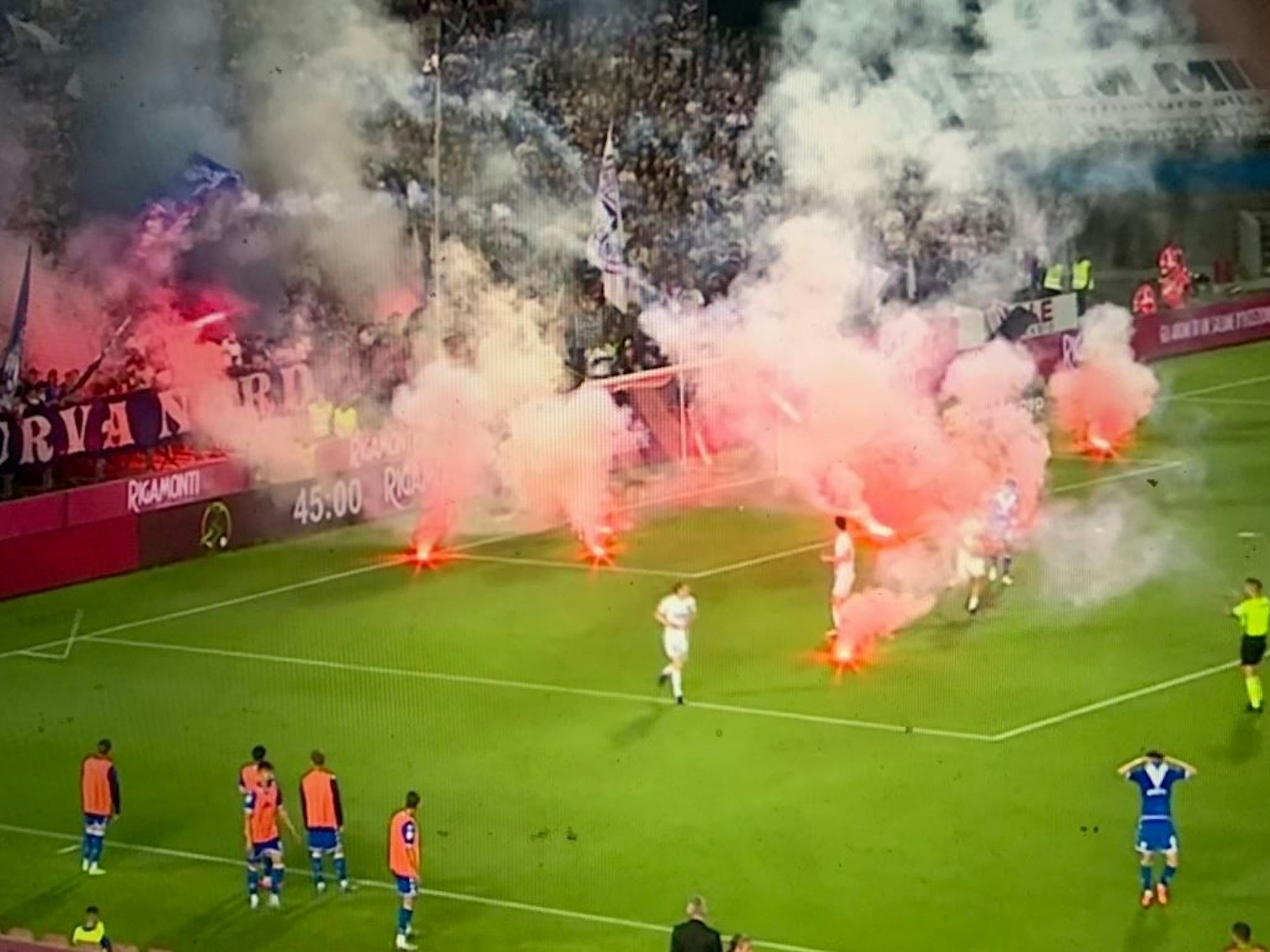Die Spieler von Brescia Calcio und Cosenza flüchten, als Knallkörper auf den Platz fliegen.
