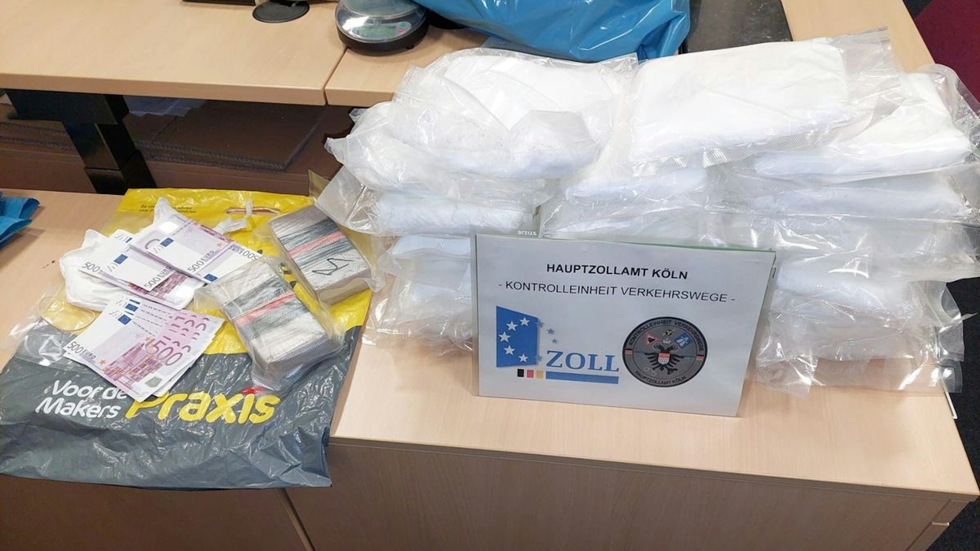Auf einem Tisch ist Falschgeld und verpackte Drogen zu sehen.