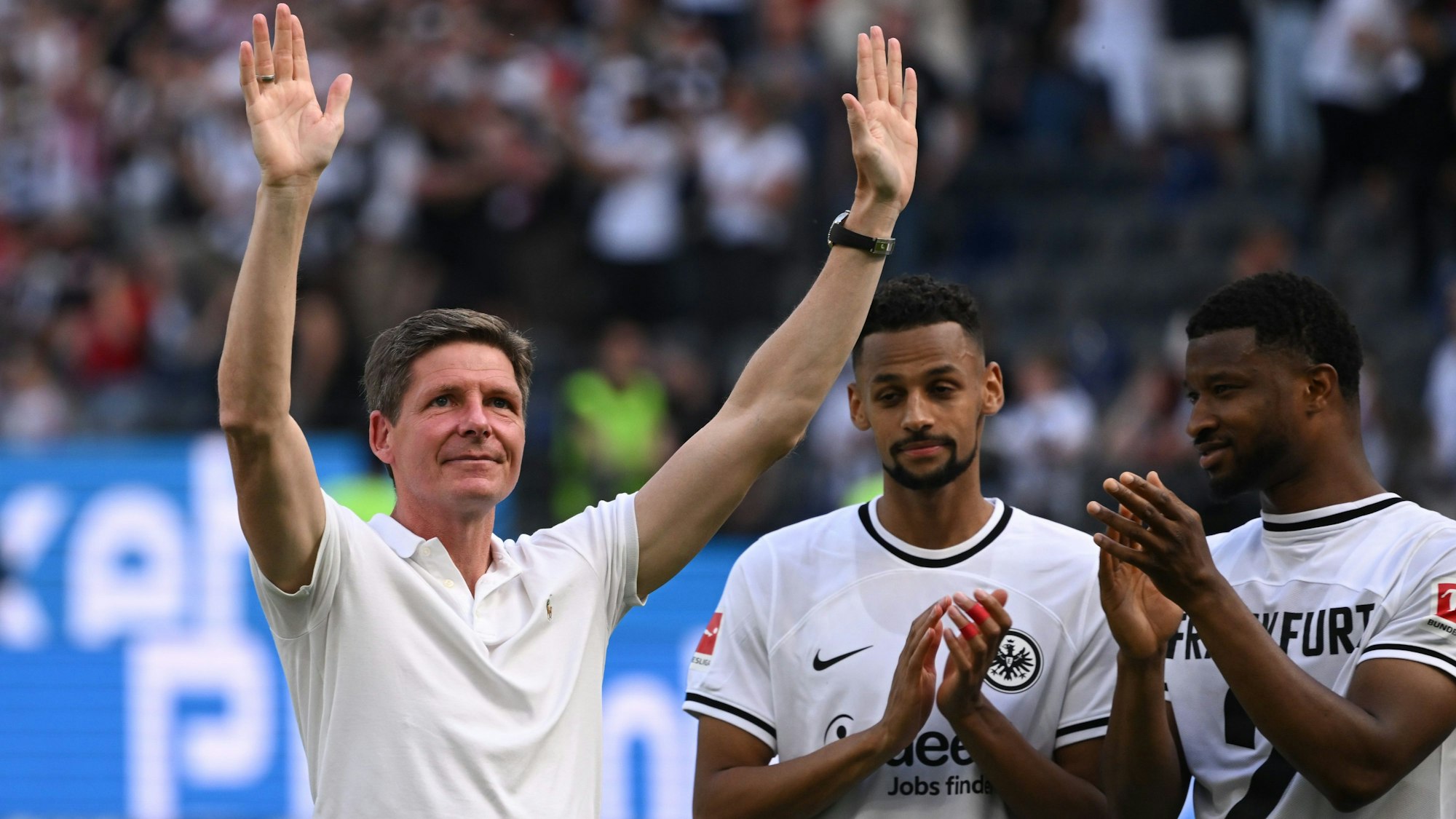 Frankfurts Cheftrainer Oliver Glasner (l) winkt nach dem Spiel neben Djibril Sow (M) und Almamy Touré zu den Fans.