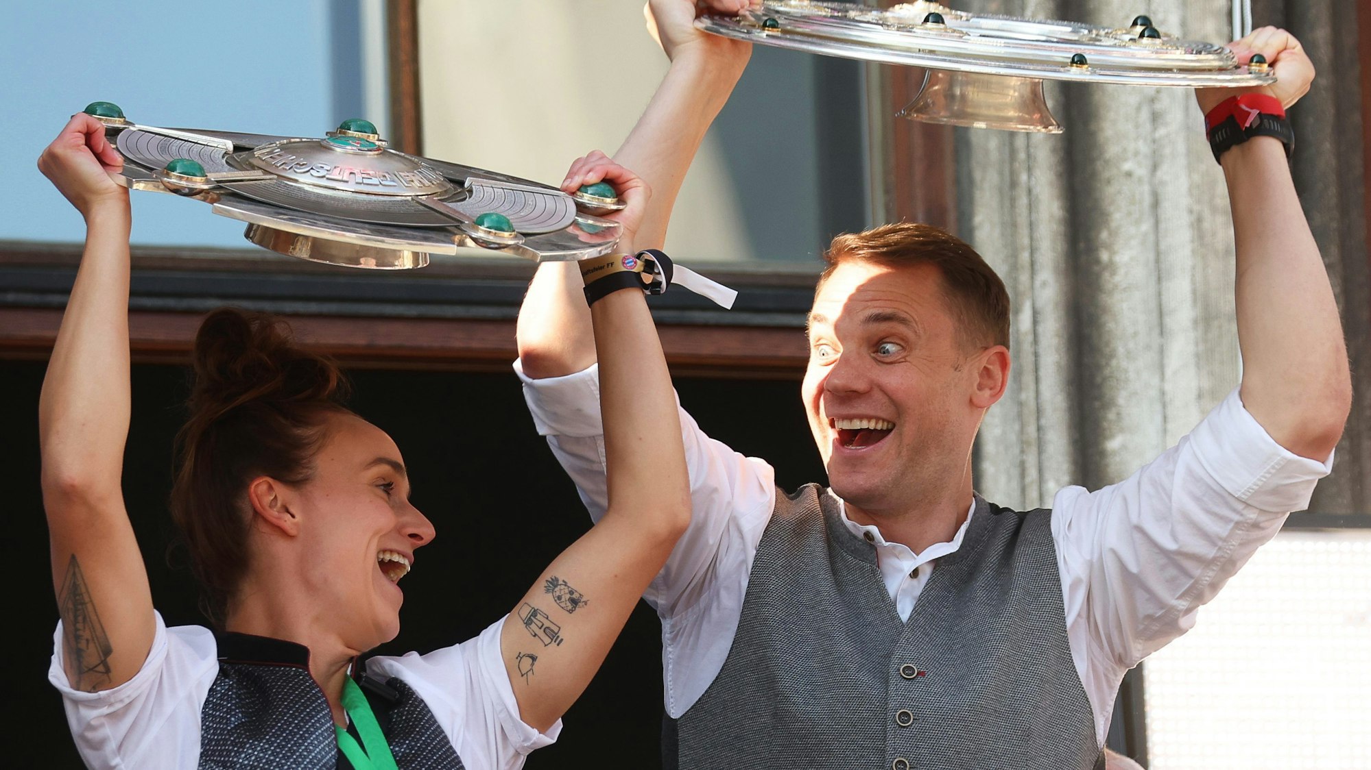 Lina Magull und Manuel Neuer halten die Meisterschalen auf dem Rathausbalkon in München hoch und jubeln.