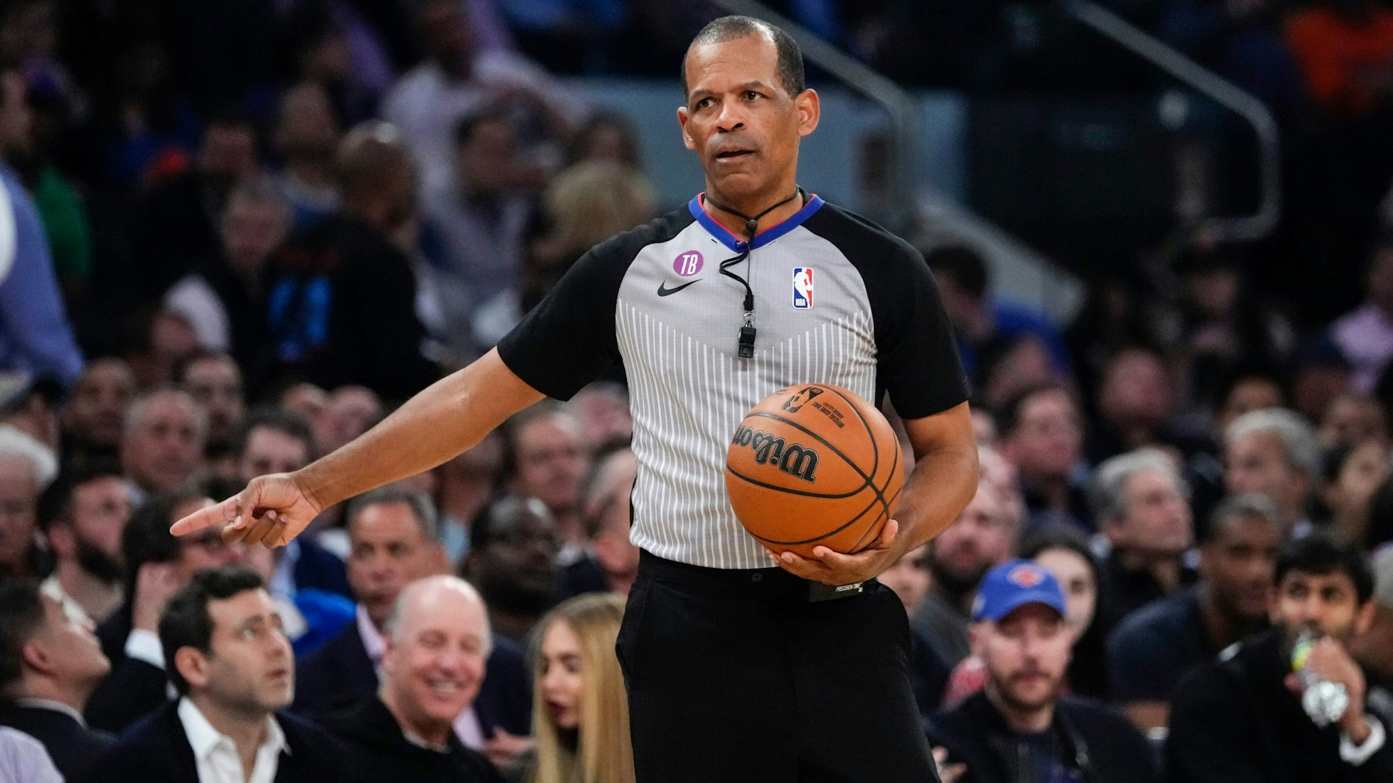 NBA-Schiedsrichter Eric Lewis hält einen Basketball in der Hand.