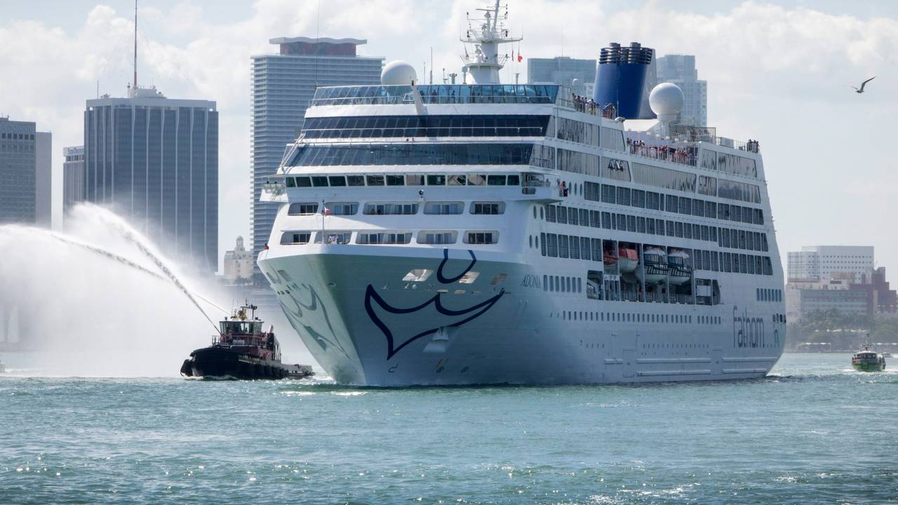 Ein Kreuzfahrtschiff auf dem Meer, im Hintergrund Wolkenkratzer.