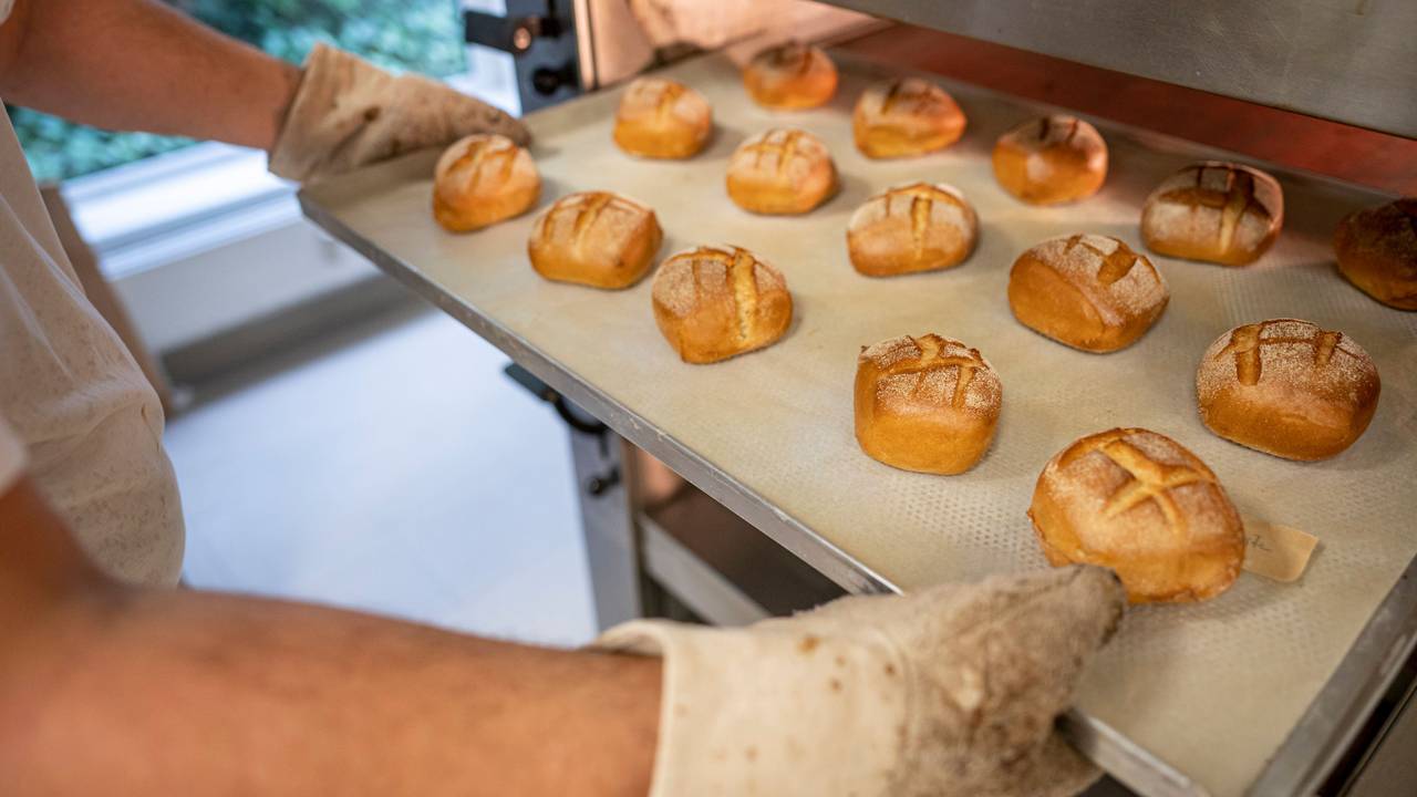 Eine Person schiebt in der Bäcker-Innung Berlin Blech mit Brötchen in den Ofen.