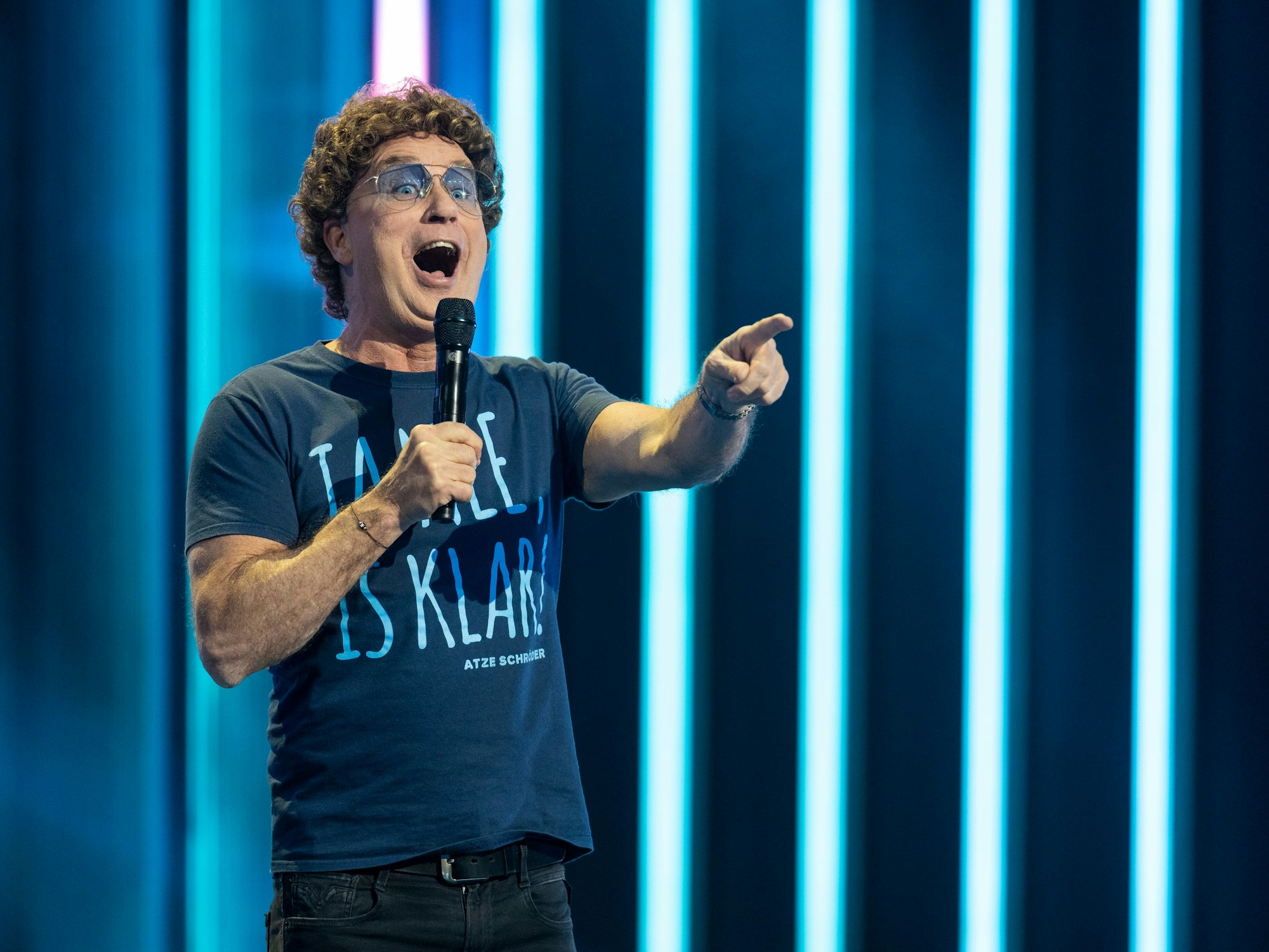 Atze Schröder steht auf der Bühne und spricht mit dem Publikum.