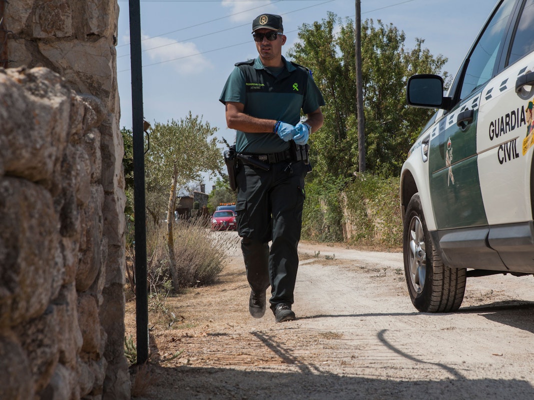 Ein Mitglied der Polizeieinheit „Guardia Civil“ geht zwischen einem Fahrzeug der „Guarda Civil“ und einer Mauer entlang.