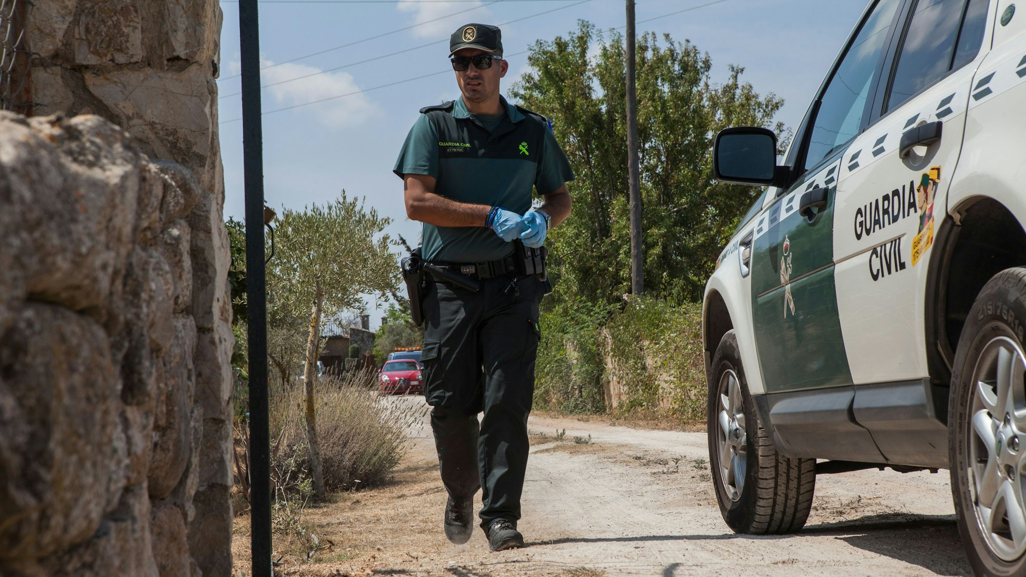 Ein Mitglied der Polizeieinheit „Guardia Civil“ geht zwischen einem Fahrzeug der „Guarda Civil“ und einer Mauer entlang.