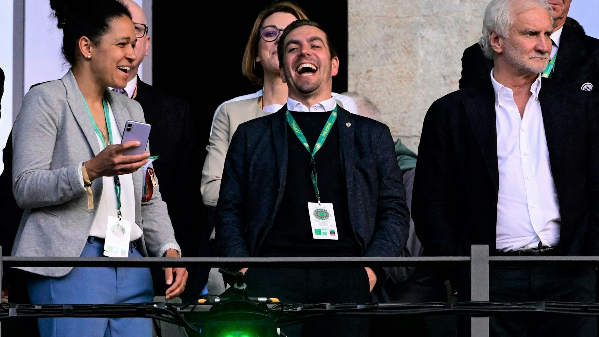 Philipp Lahm lacht auf der Tribüne beim Finale des DFB-Pokals neben Celia Sasic und Rudi Völler.