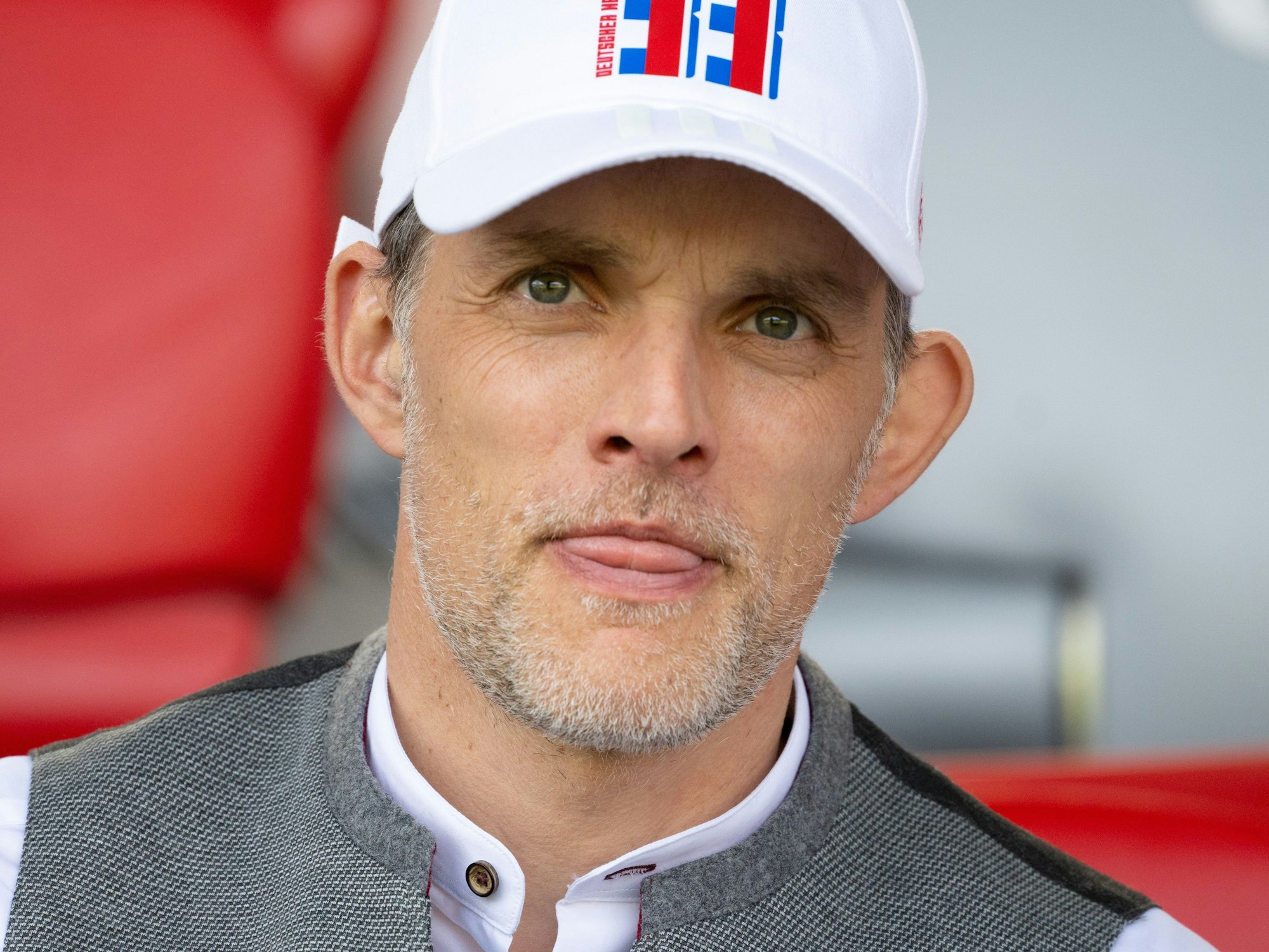 Trainer Thomas Tuchel streckt auf der Tribüne die Zunge raus.