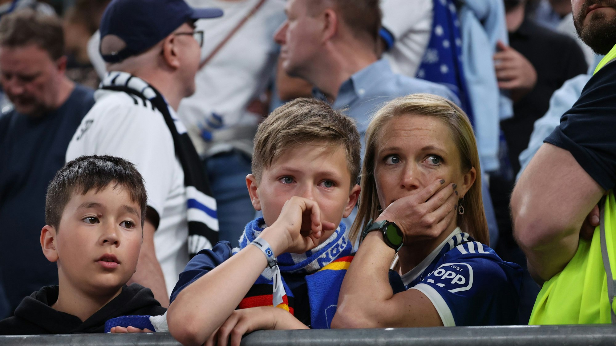 Enttäuschte HSV-Fans sitzen nach Spielende mit Tränen in den Augen in ihrem Fanblock.