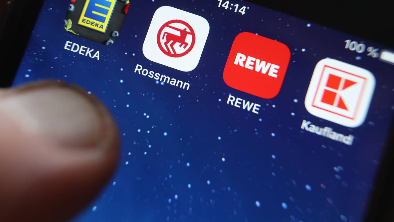Icons der Apps von den Handelsketten Edeka, Rossmann, REWE und Kaufland sind auf dem Display eines iPhones zu sehen.