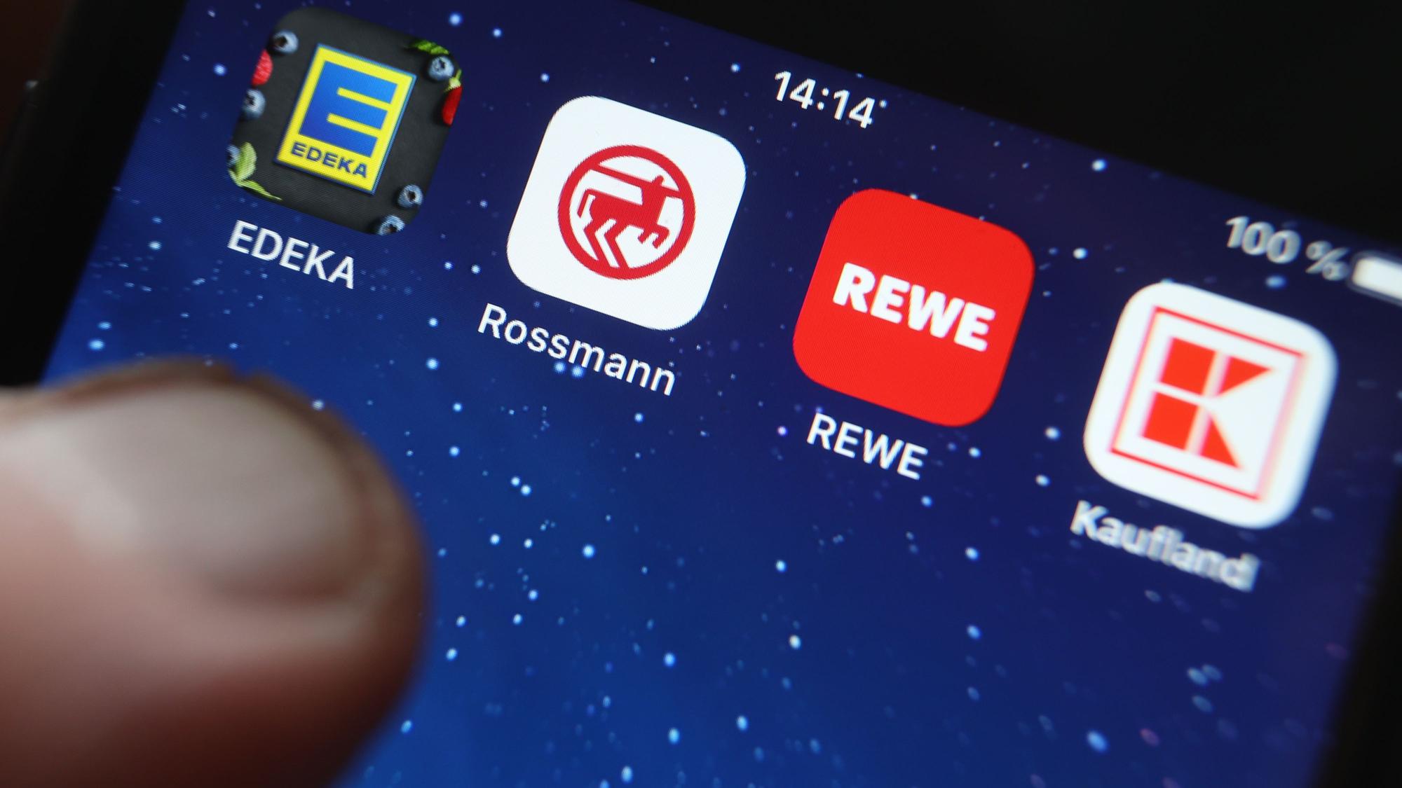 Icons der Apps von den Handelsketten Edeka, Rossmann, REWE und Kaufland sind auf dem Display eines iPhones zu sehen.