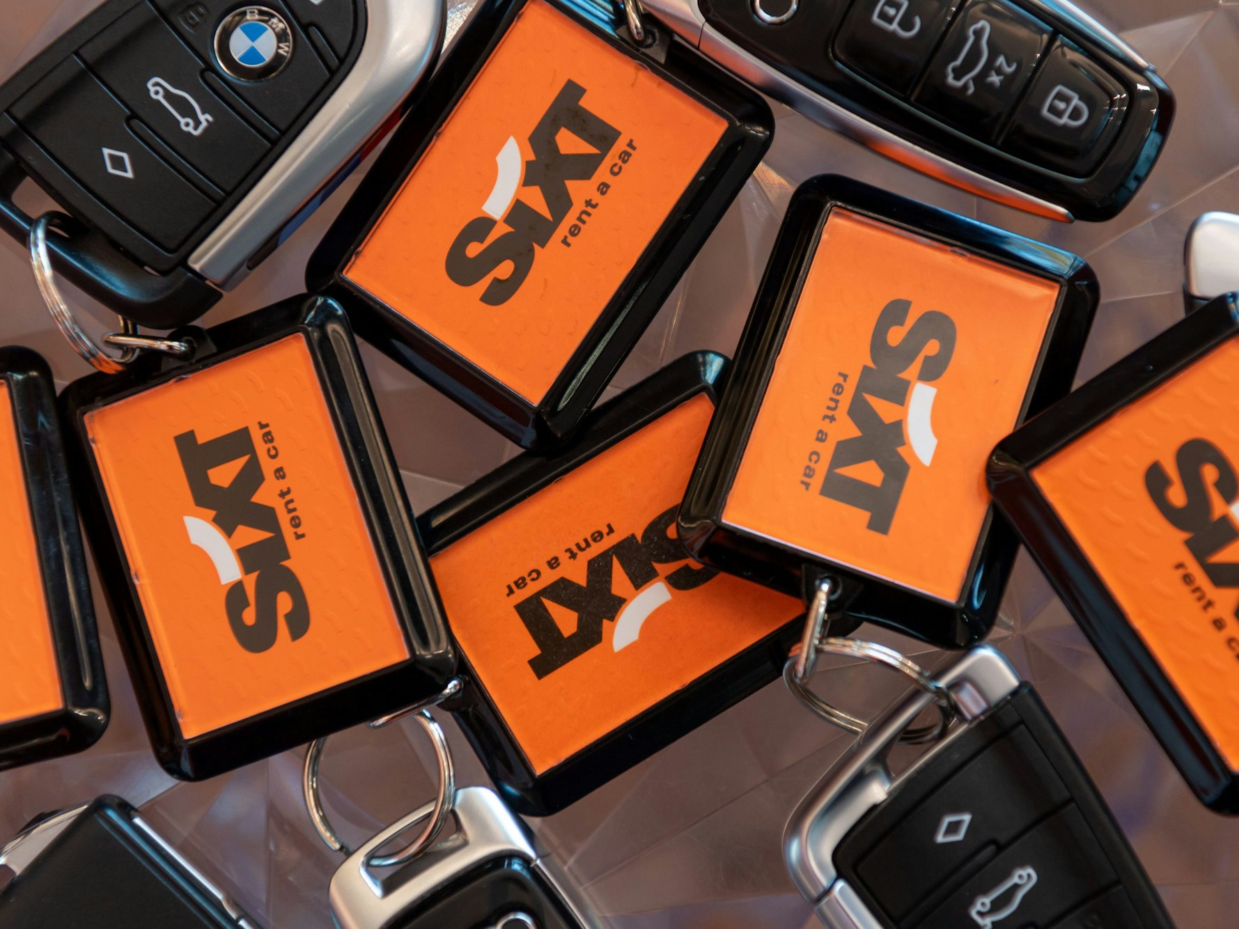 Diverse Schlüssel mit dem Sixt-Logo liegen zusammen.