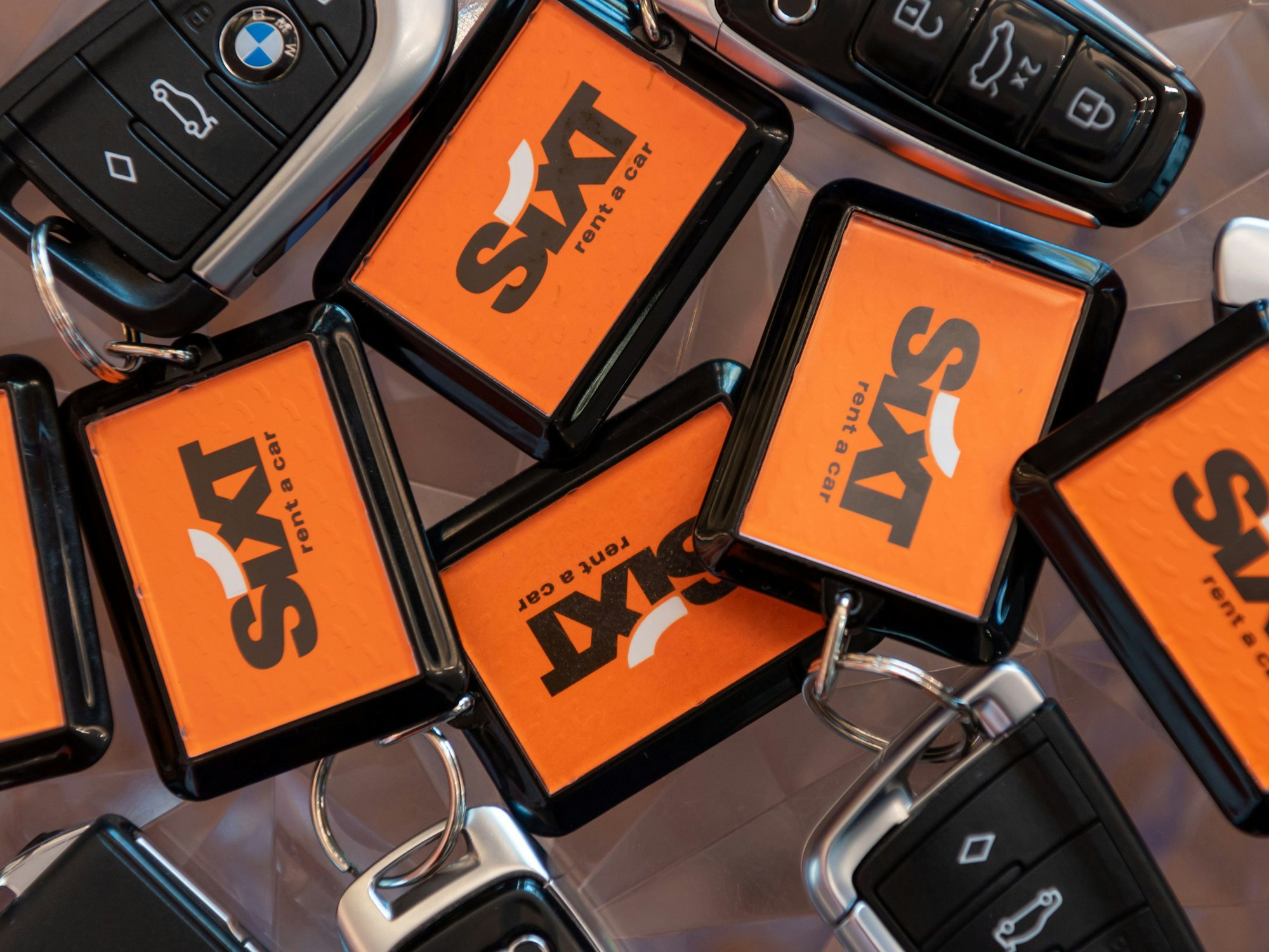 Diverse Schlüssel mit dem Sixt-Logo liegen zusammen.