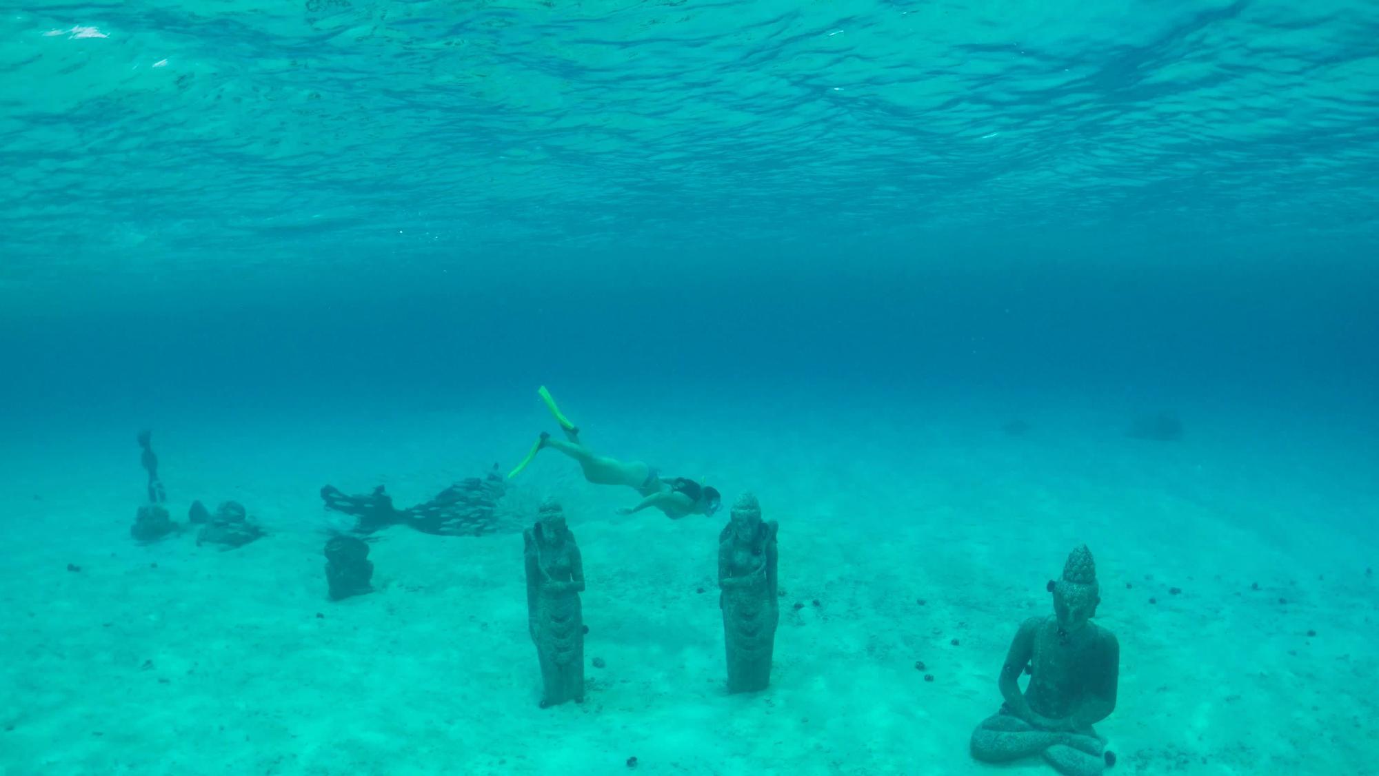 Taucherin schwimmt bei versunkenen Statuen in Bora Bora.