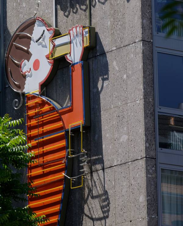 Eine Werbetafel der Kölsch-Brauerei Reissdorf an einem Haus zeigt eine Figur, die Kölsch trinkt.