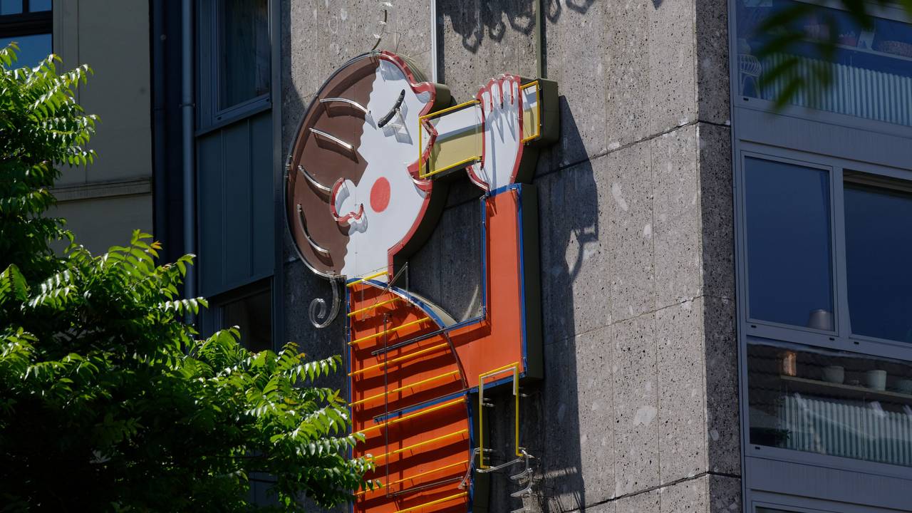 Eine Werbetafel der Kölsch-Brauerei Reissdorf an einem Haus zeigt eine Figur, die Kölsch trinkt.