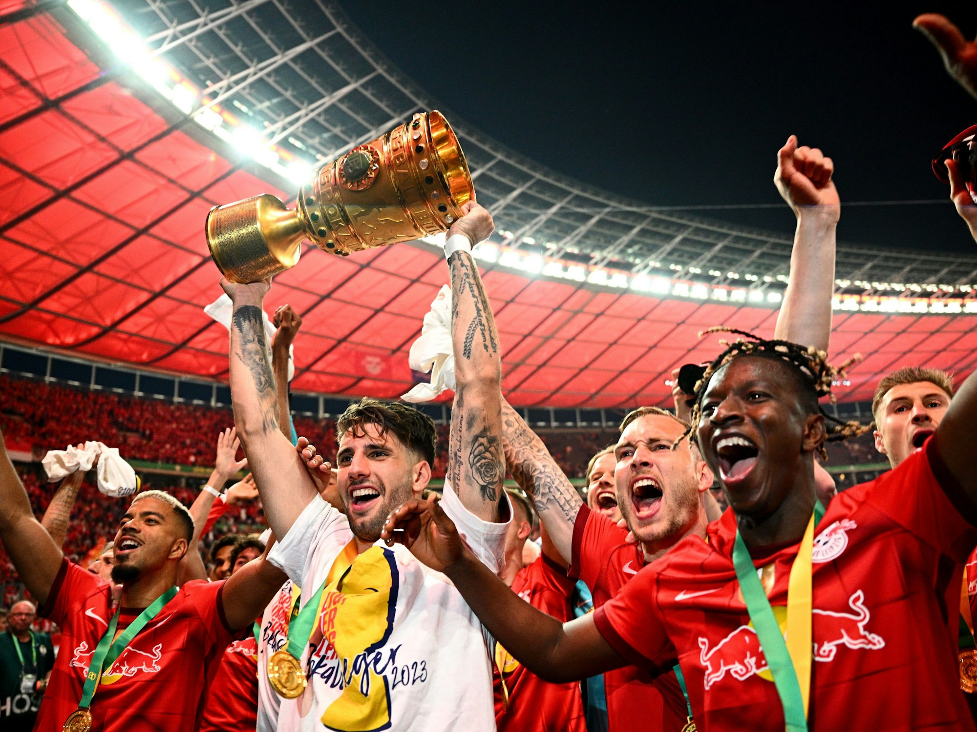 Leipzigs Dominik Szoboszlai (2.v.l.) hält die Siegertrophäe in die Höhe und bejubelt mit seinen Teamgefährten den Pokalsieg.