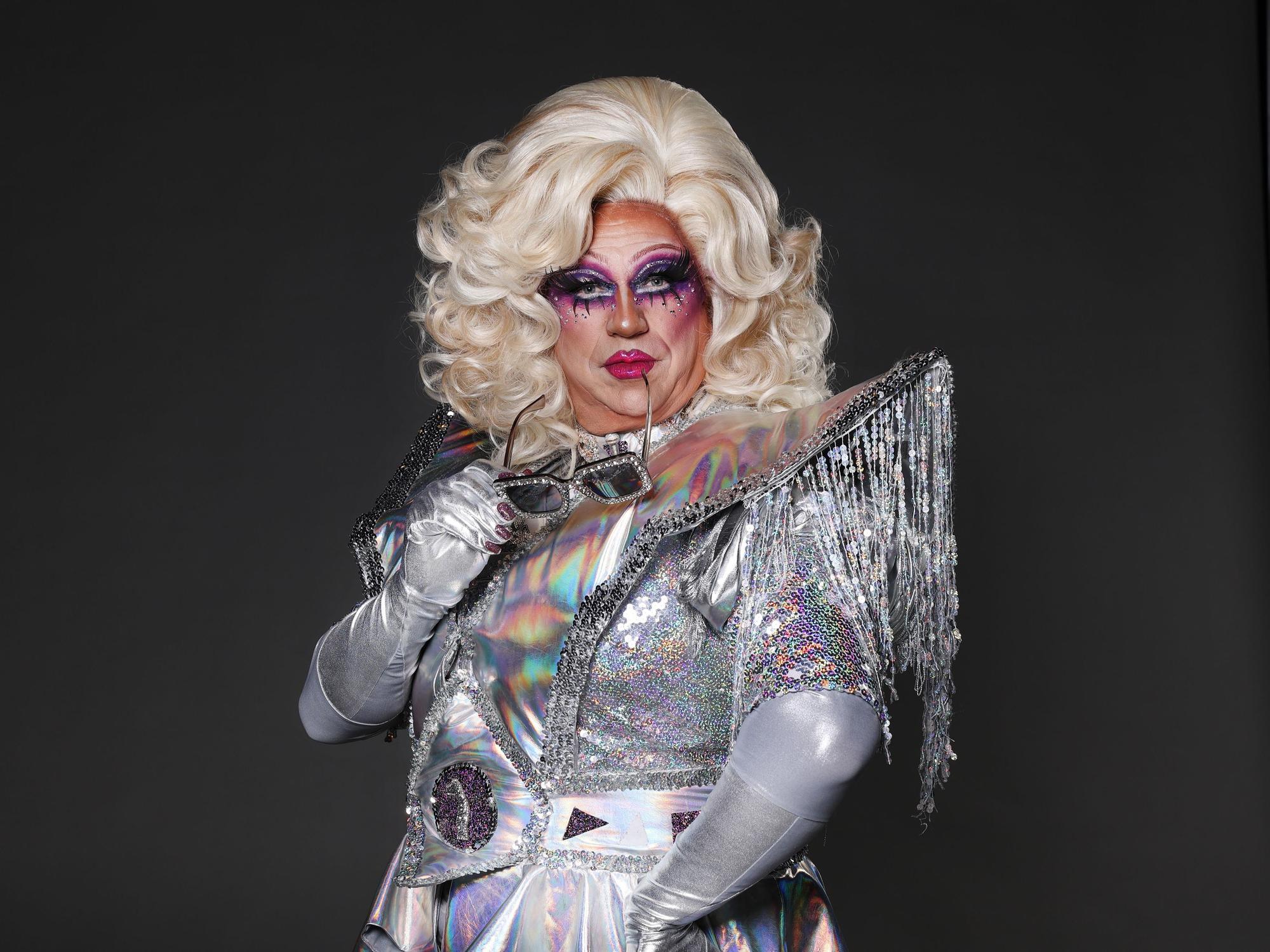 Dragqueen Sylvia Stoned hat eine Sonnenbrille im Mund.