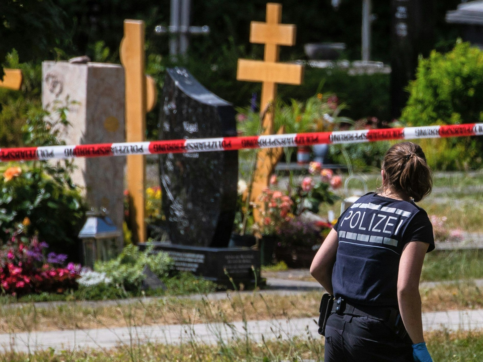 Altbach: Eine Polizistin geht über den abgesperrten Teil an einem Tatort auf einem Friedhof.