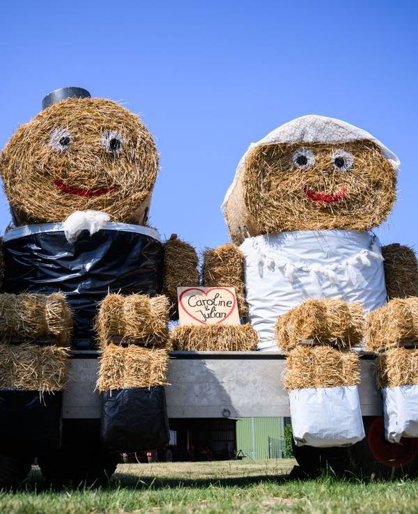 Zwei Strohfiguren in Aussehen von Braut und Bräutigam stehen zur Hochzeit von Caroline und Julian auf einem Hof in Ingeln-Oesselse in der Region Hannover.