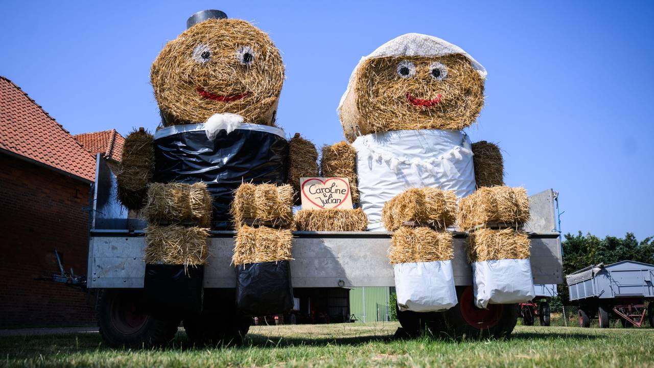 Zwei Strohfiguren in Aussehen von Braut und Bräutigam stehen zur Hochzeit von Caroline und Julian auf einem Hof in Ingeln-Oesselse in der Region Hannover.
