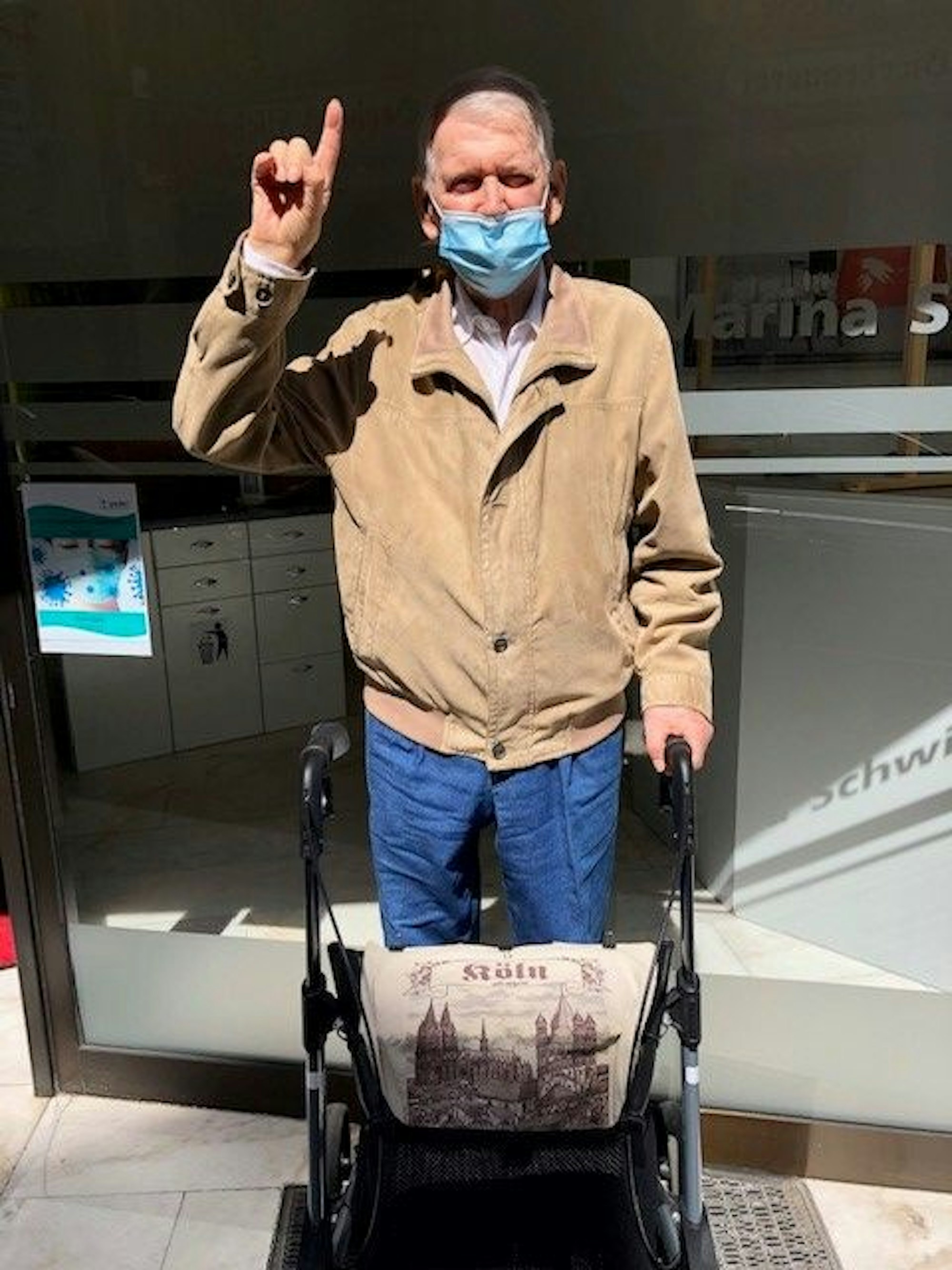 Paul Brandt (92) aus Köln schaut in die Kamera, während er sich an seinem Rollator festhält.