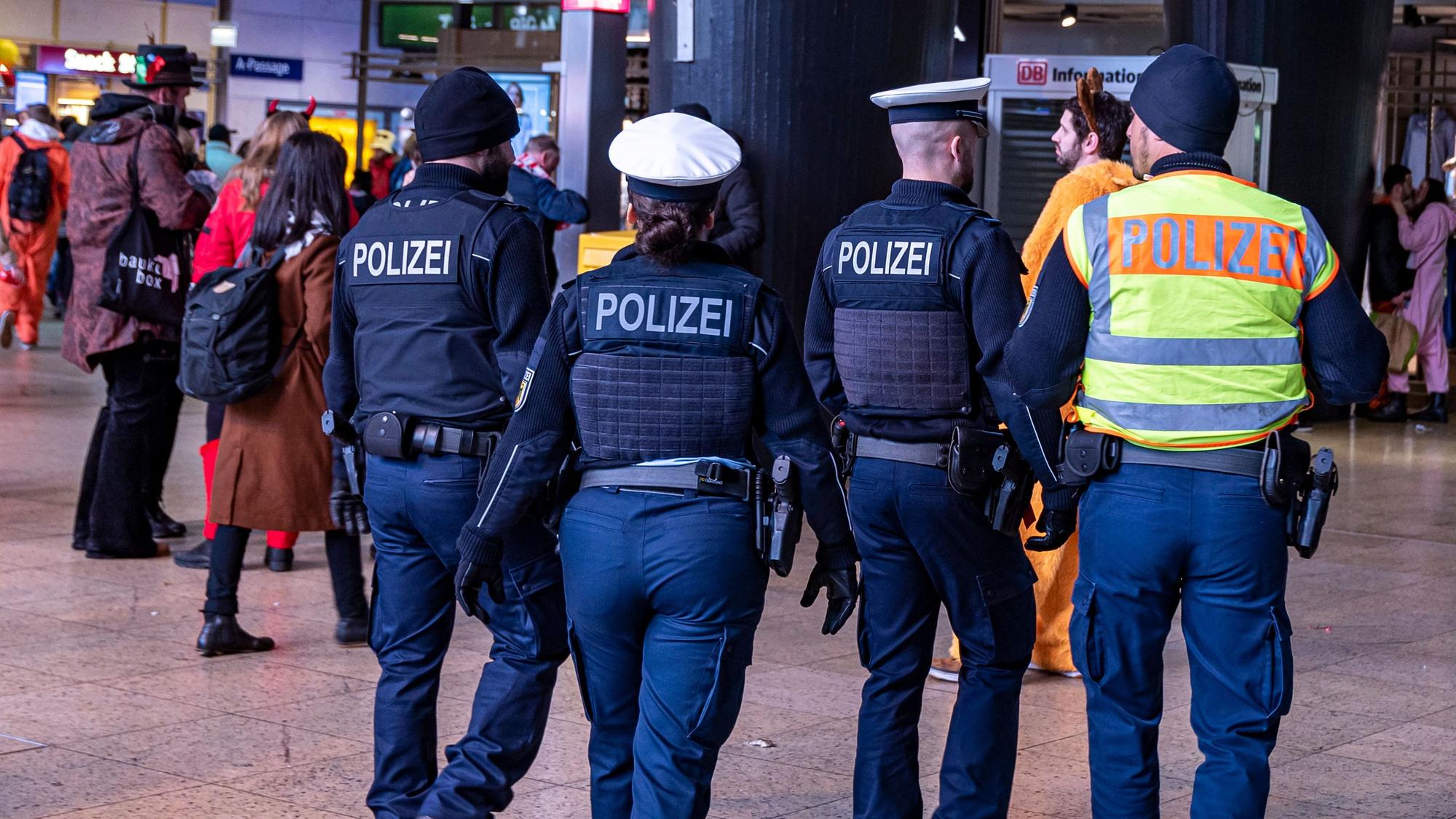 Vier Einsatzkräfte der Polizei laufen durch den Kölner Hauptbahnhof.
