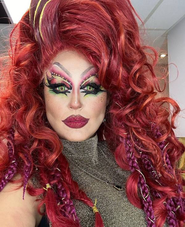 Moderatorin Nina Moghaddam als Drag-Queen mit buntem Make-up und roter Perücke bei der Show „Viva la Diva – Wer ist die Queen?“.