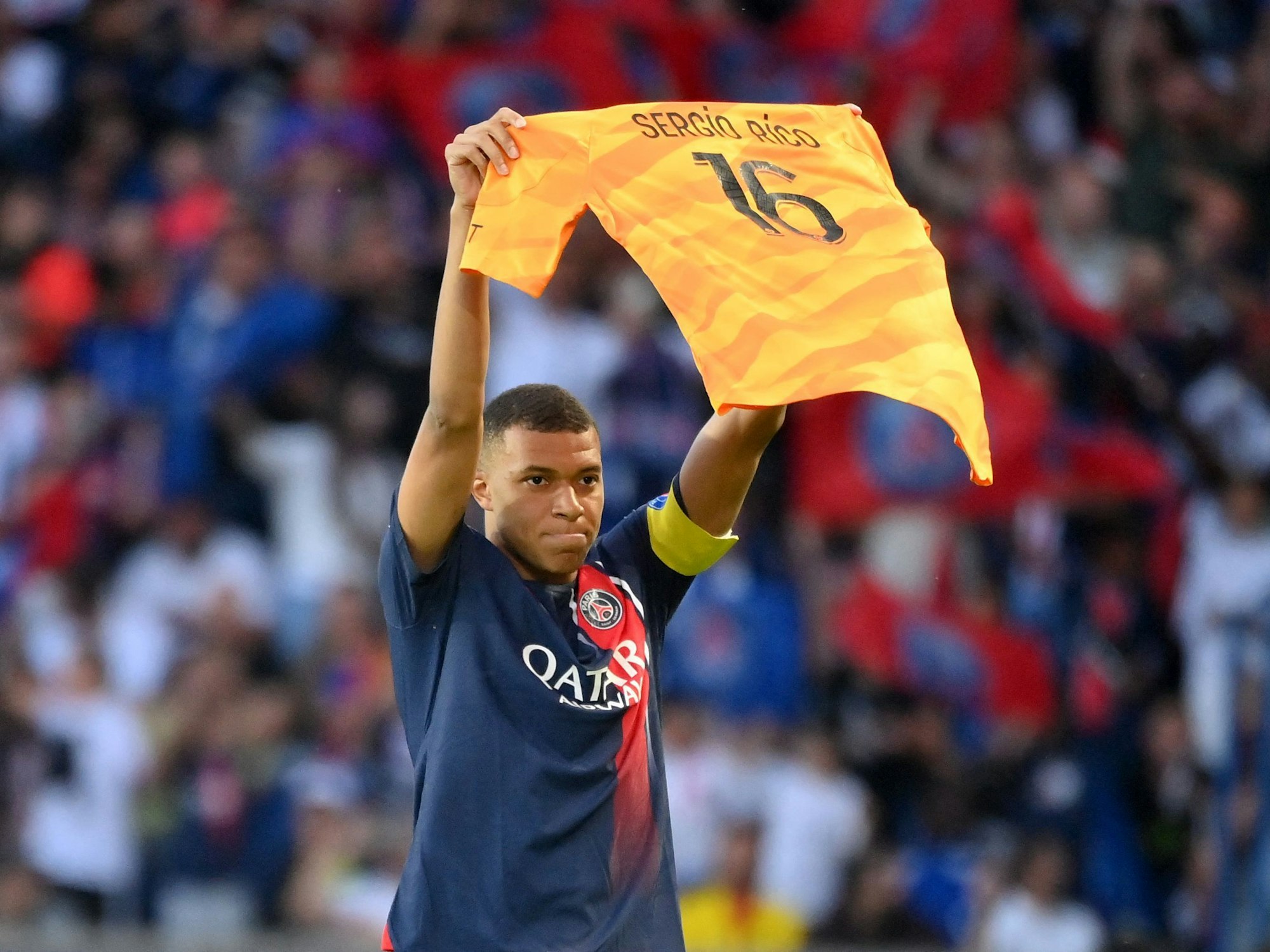 Kylian Mbappe hält das Trikot von Sergio Rico hoch.