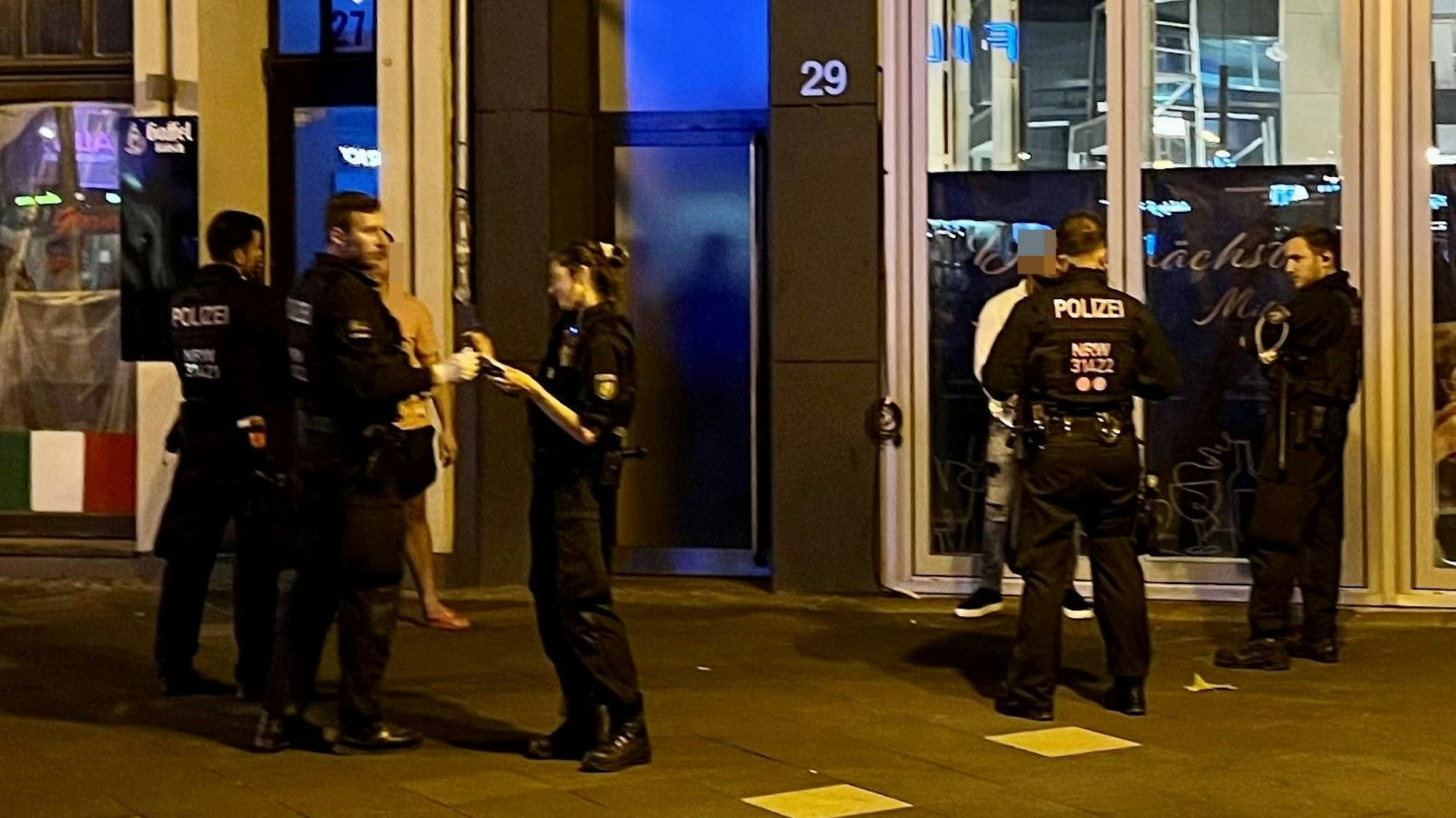 Einsatzkräfte der Polizei kontrollieren an einer Hauswand einen Mann wegen möglichen Waffenbesitzes.