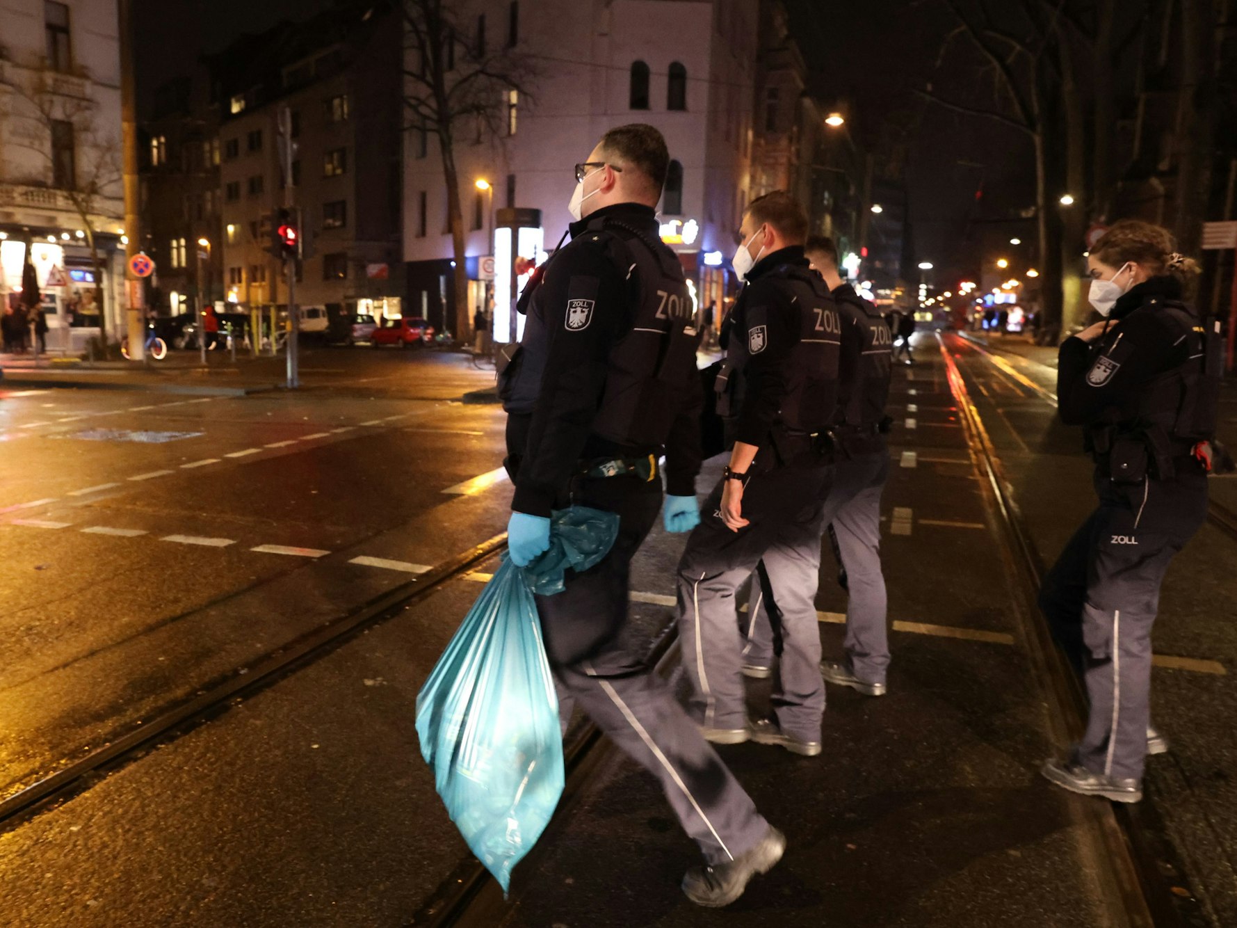 Einsatzkräfte des Kölner Zolls gehen mit sichergestellter Ware auf den Ringen in Köln umher.