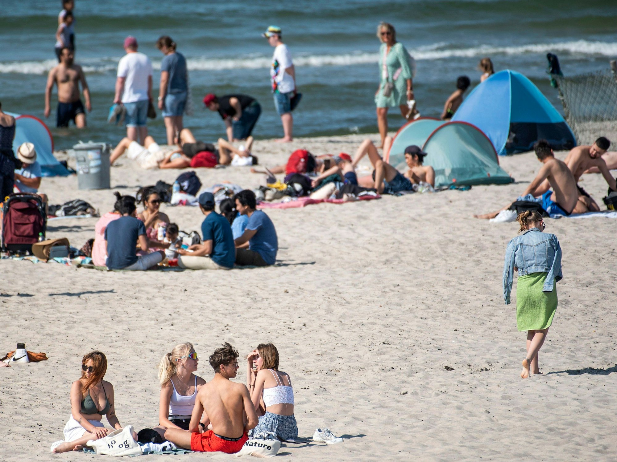 Badegäste genießen am Ostseestrand von Warnemünde die Sonne.