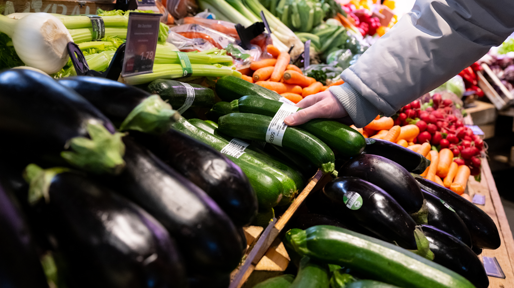 Ein Mann steht in einem Supermarkt an einer Auslage in der Obst und Gemüseabteilung.