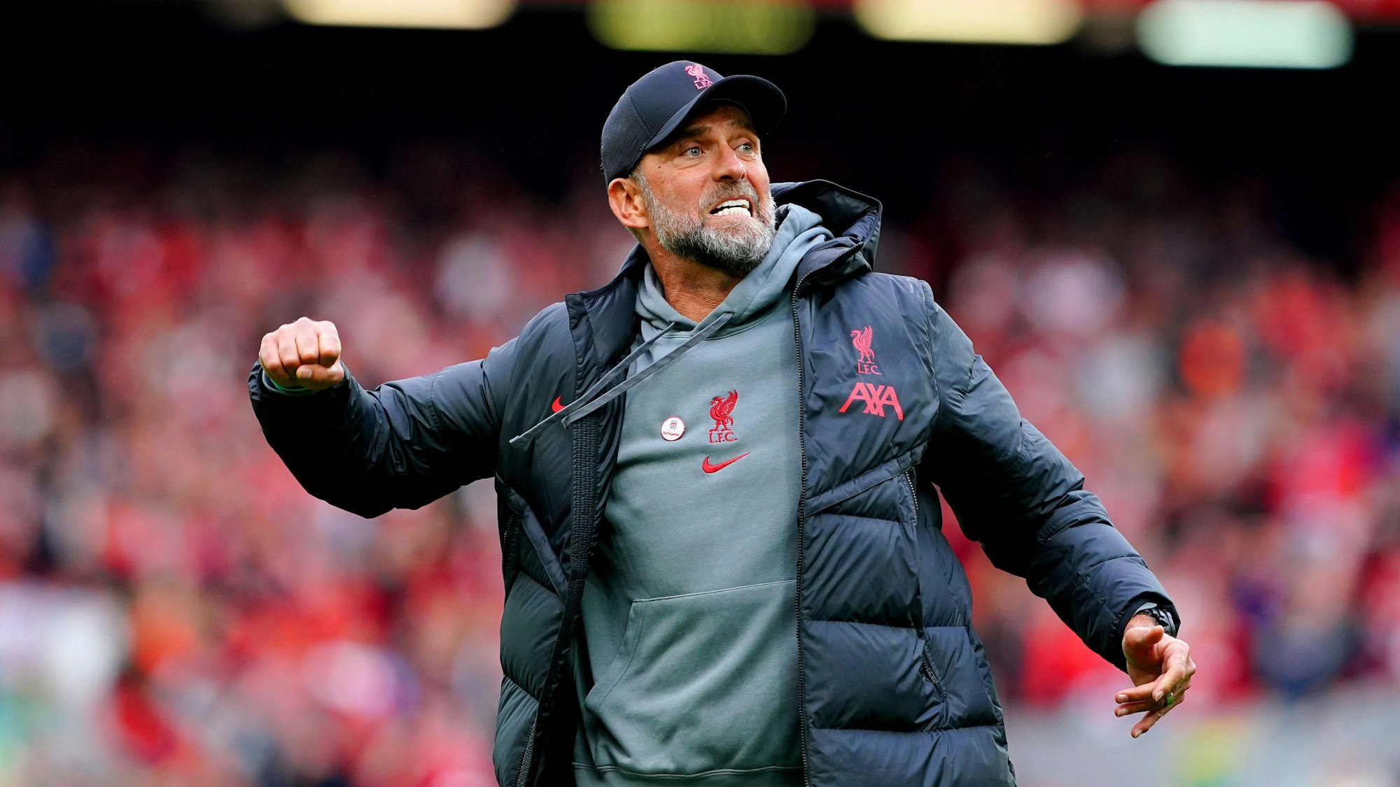 Jürgen Klopp springt mit geballter Faust in die Luft. Er trägt Klamotten seines Vereins FC Liverpool.