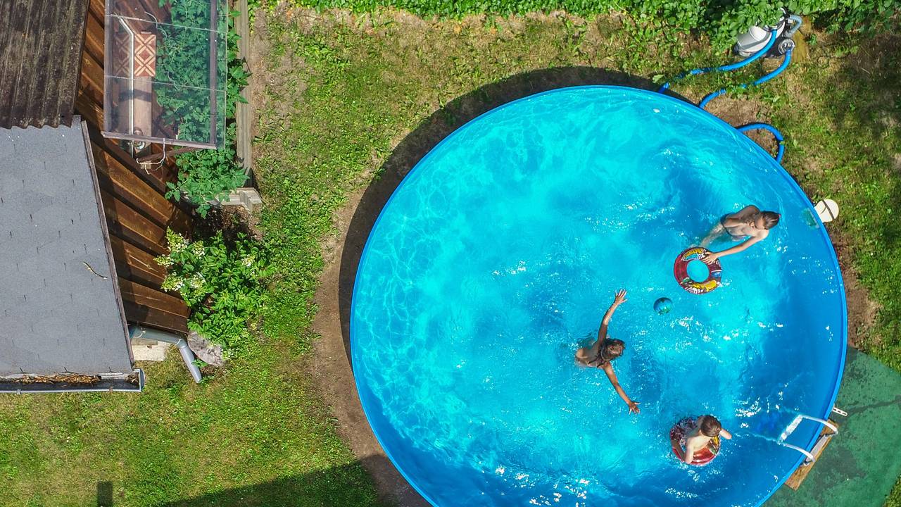 Kinder planschen in einem Pool in einem Garten.