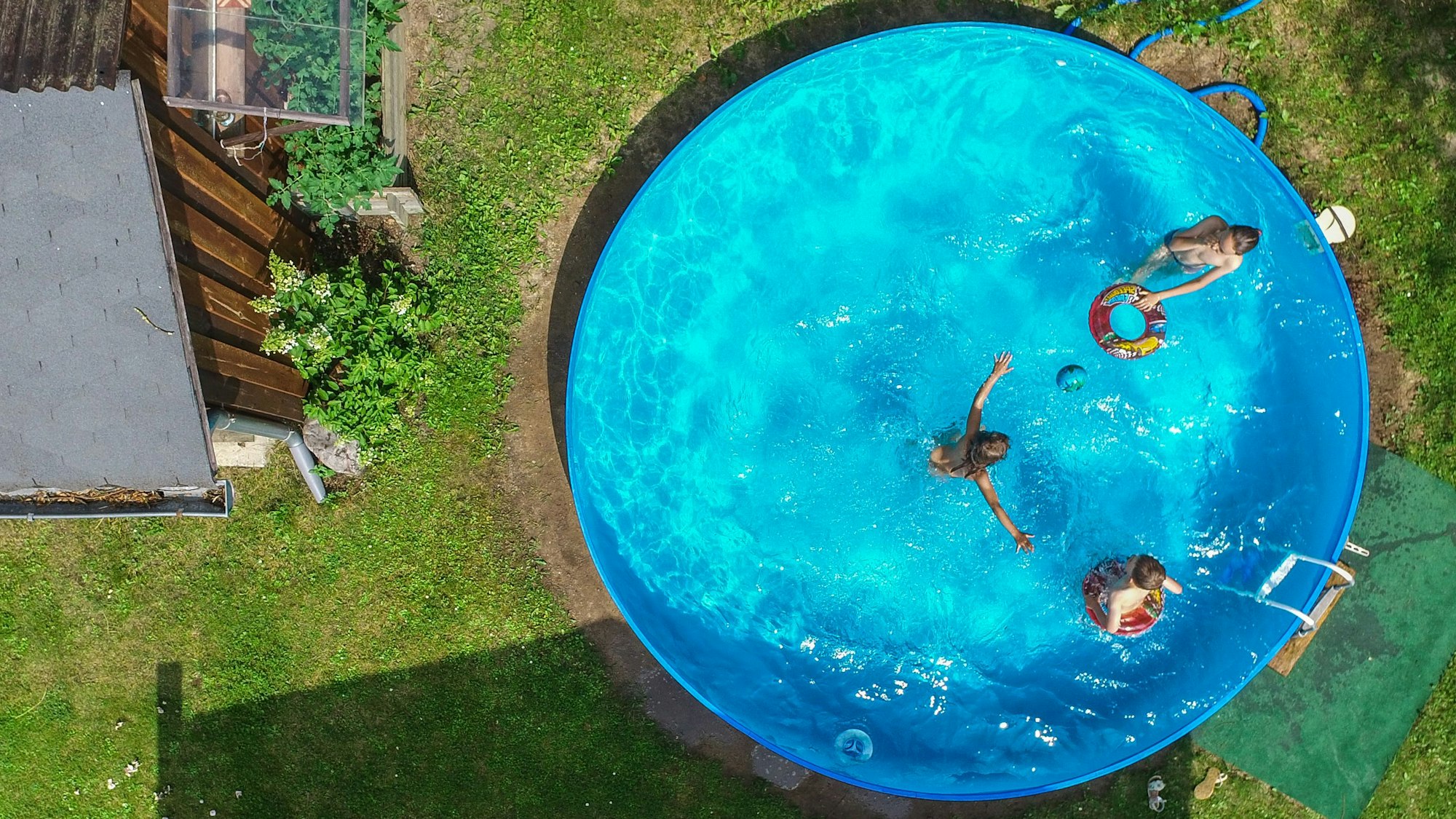 Kinder planschen in einem Pool in einem Garten.